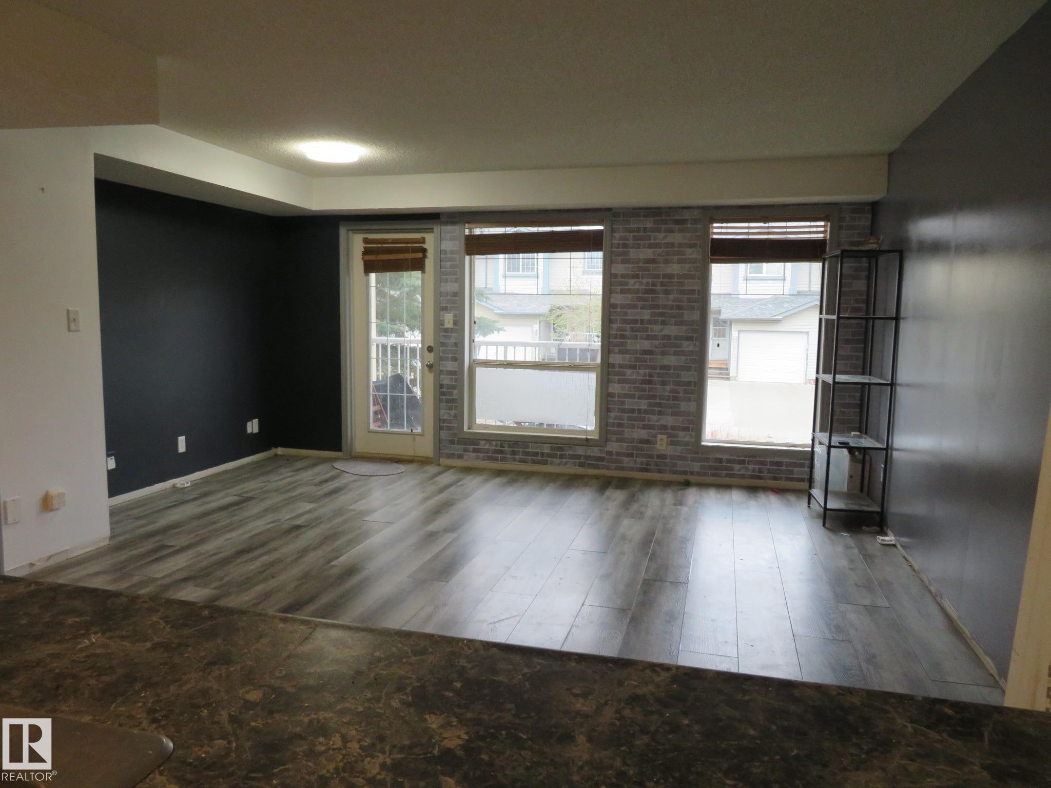 Spacious living area featuring wood-finish flooring, accent walls, and multiple windows for natural illumination - 2945 26 Street, Edmonton, AB - Indoor Photo Showing Other Room