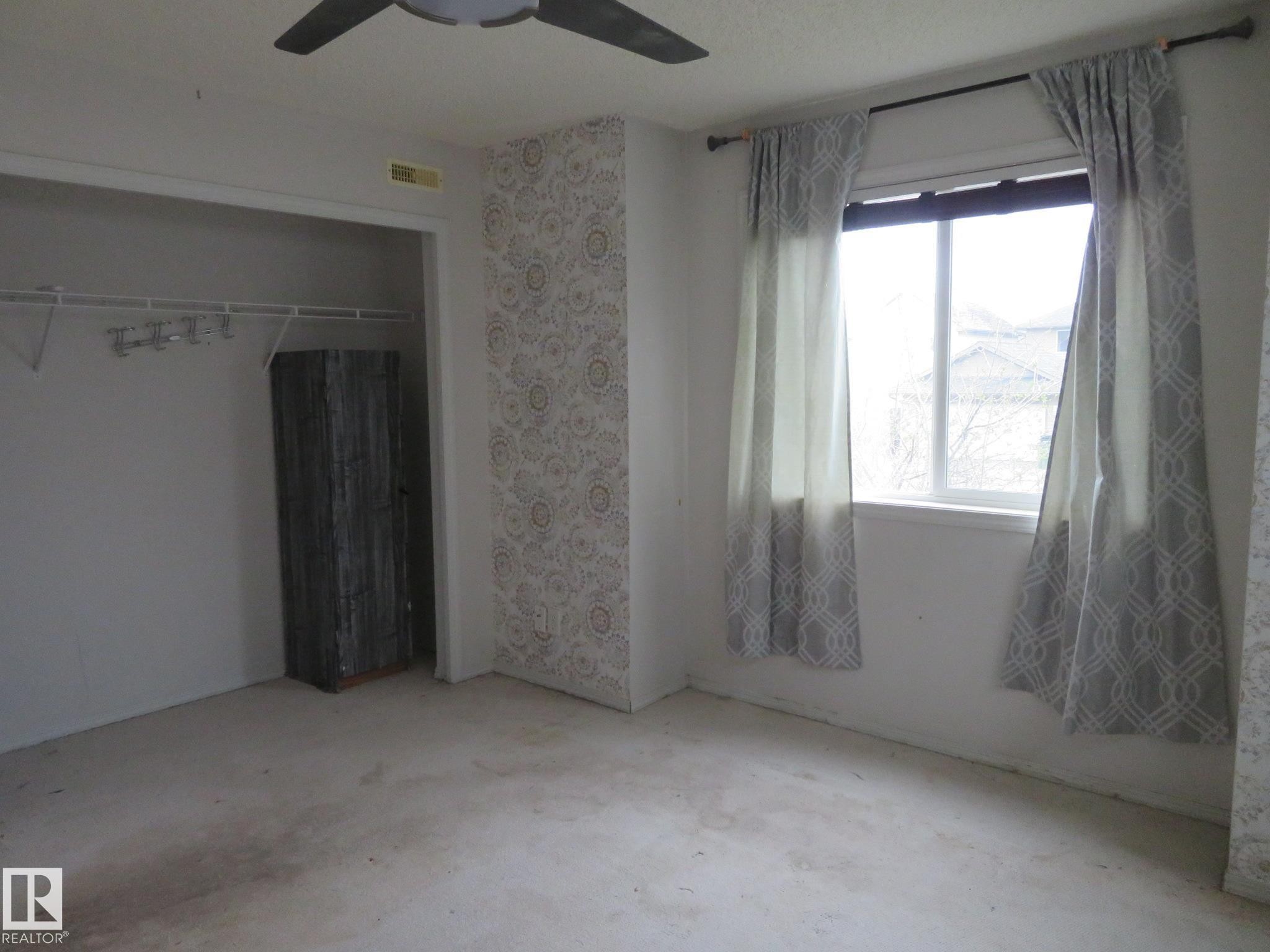 Room featuring a ceiling fan with light fixture, window with curtains, and an open closet with built-in shelving - 2945 26 Street, Edmonton, AB - Indoor