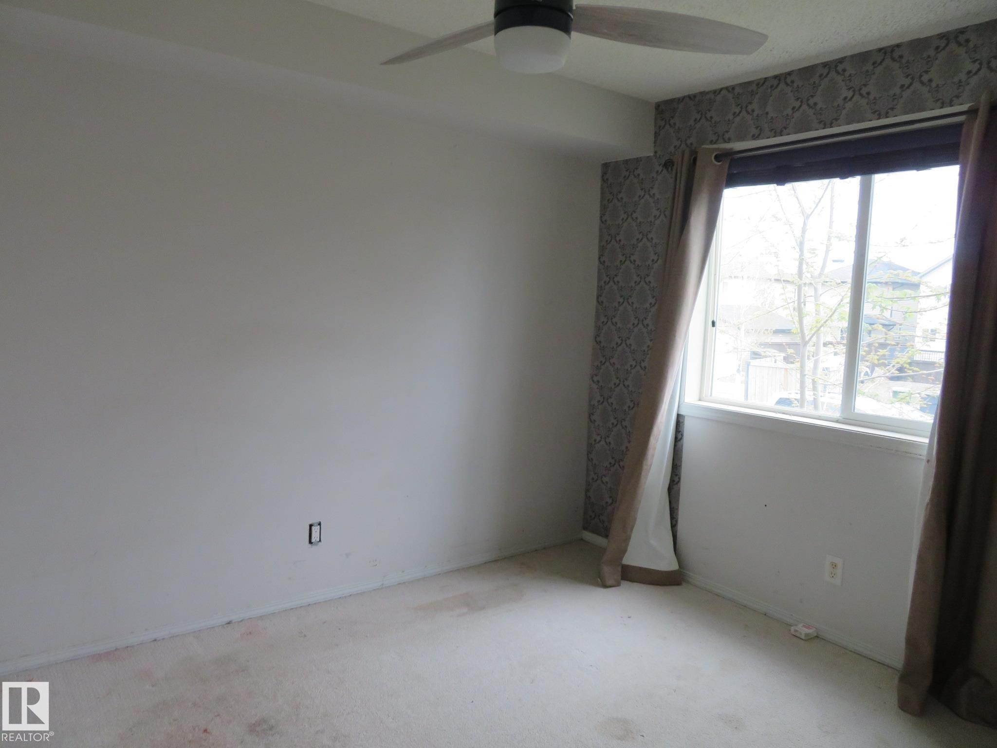 Room featuring a large window, a ceiling fan, and a patterned accent wall - 2945 26 Street, Edmonton, AB - Indoor