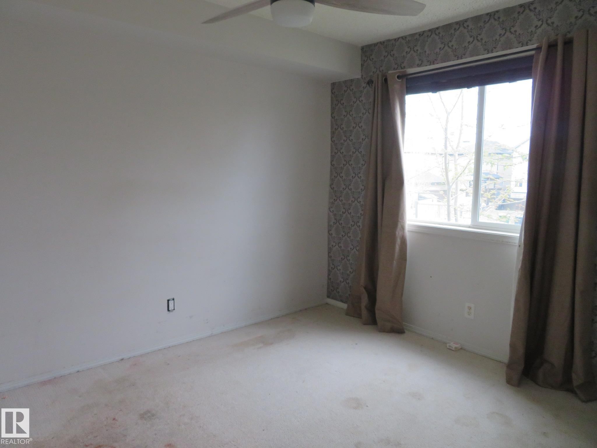 Room featuring a single window, a ceiling fan, and patterned wallpaper accent wall - 2945 26 Street, Edmonton, AB - Indoor