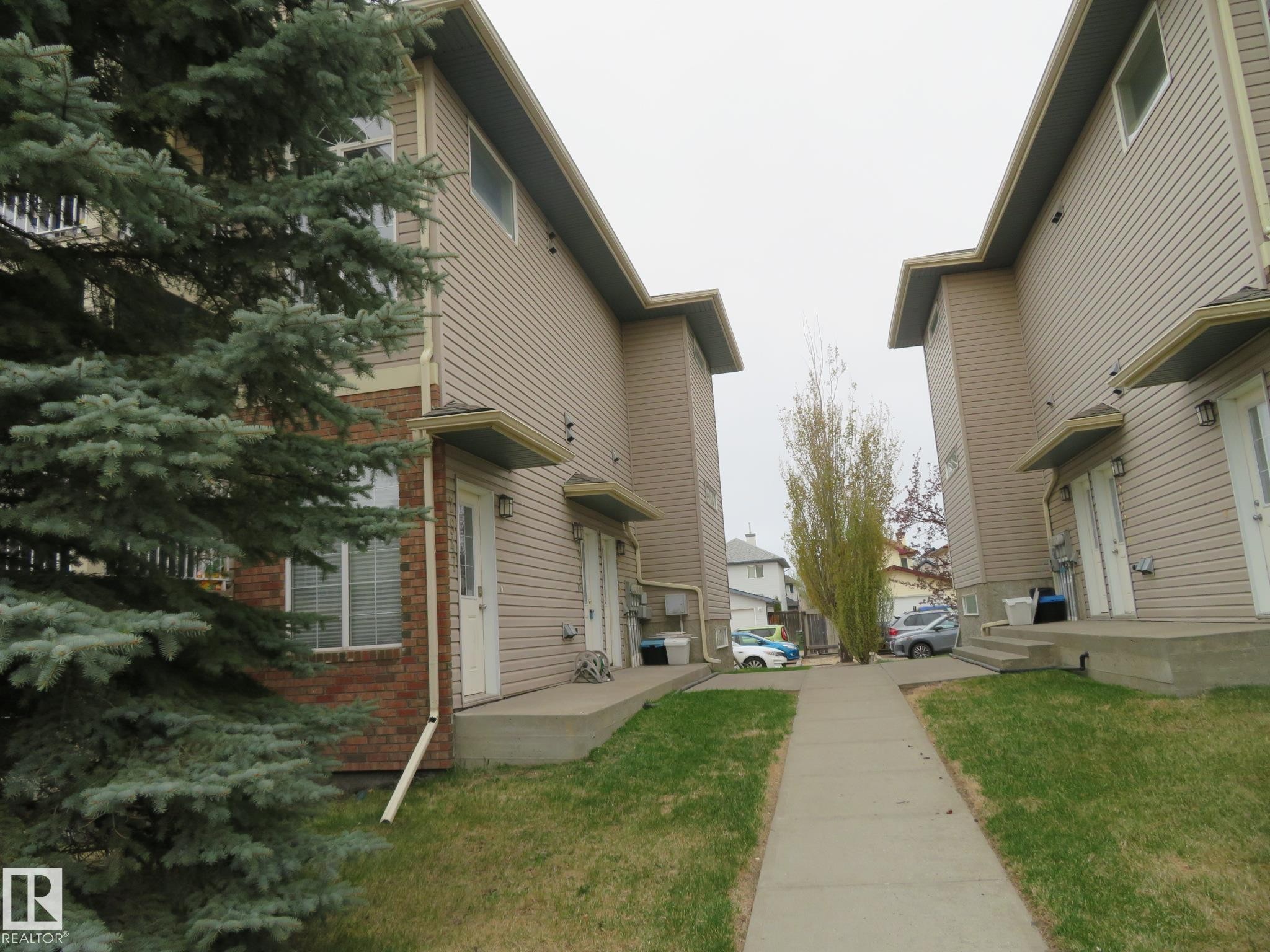 Townhome exterior featuring tan siding and brick accents - 2945 26 Street, Edmonton, AB - Outdoor