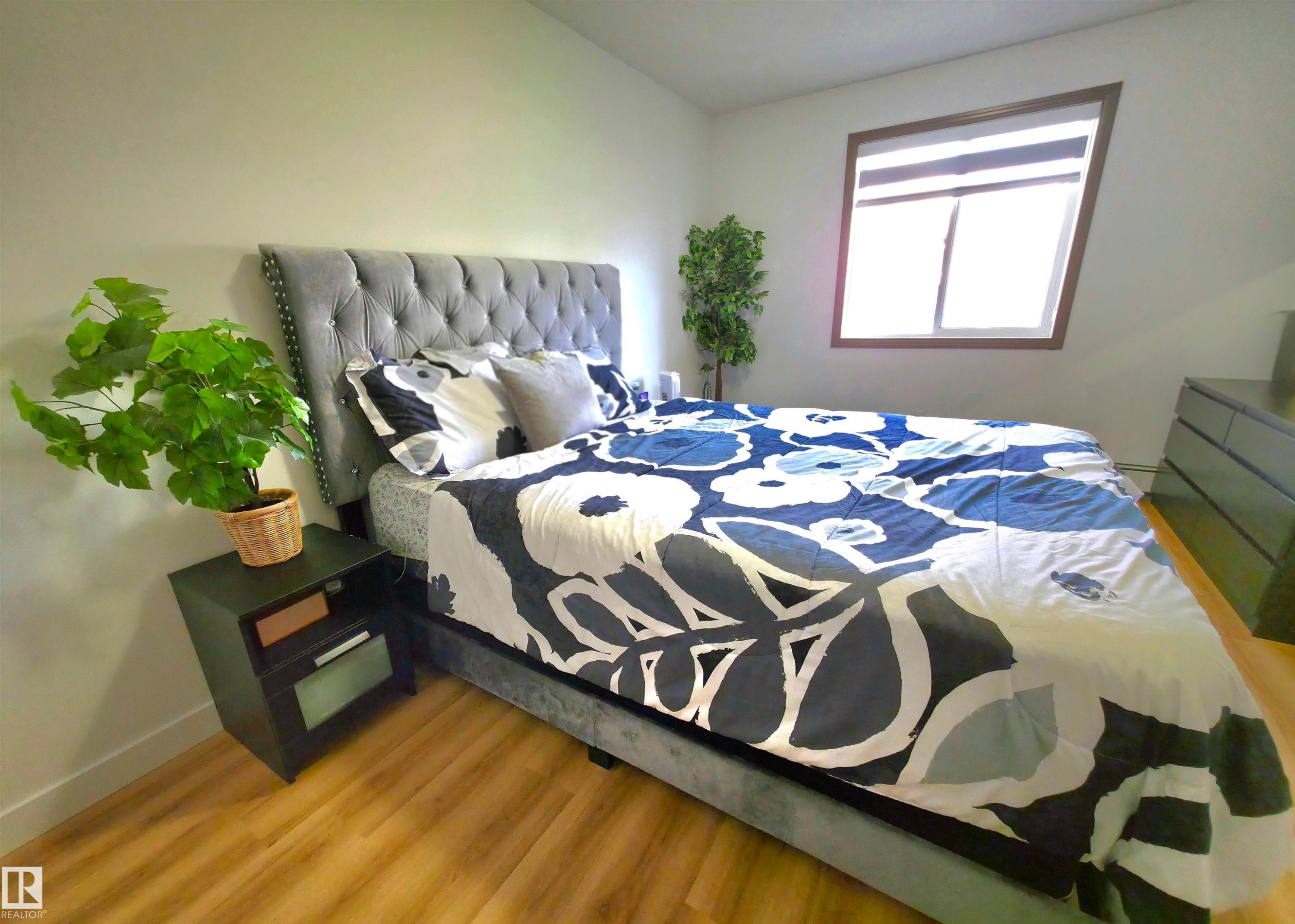 Spacious room featuring wood-finish flooring, a contemporary window with brown trim, and clean white walls - 210 5005 165 Avenue, Edmonton, AB - Indoor Photo Showing Bedroom