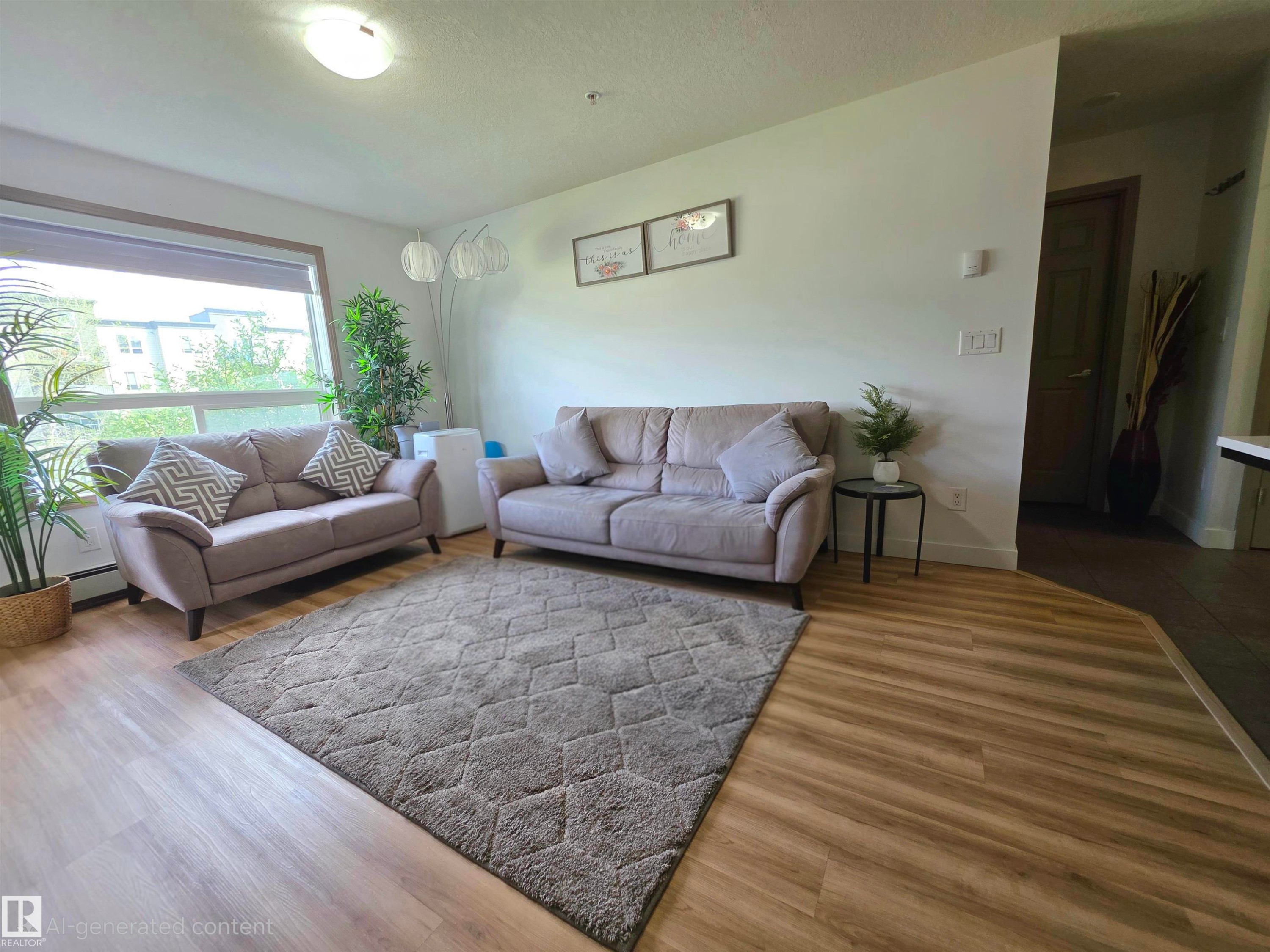 Bright room featuring wood-finish flooring, a large window, white walls, and a flush-mount ceiling light - 210 5005 165 Avenue, Edmonton, AB - Indoor Photo Showing Living Room