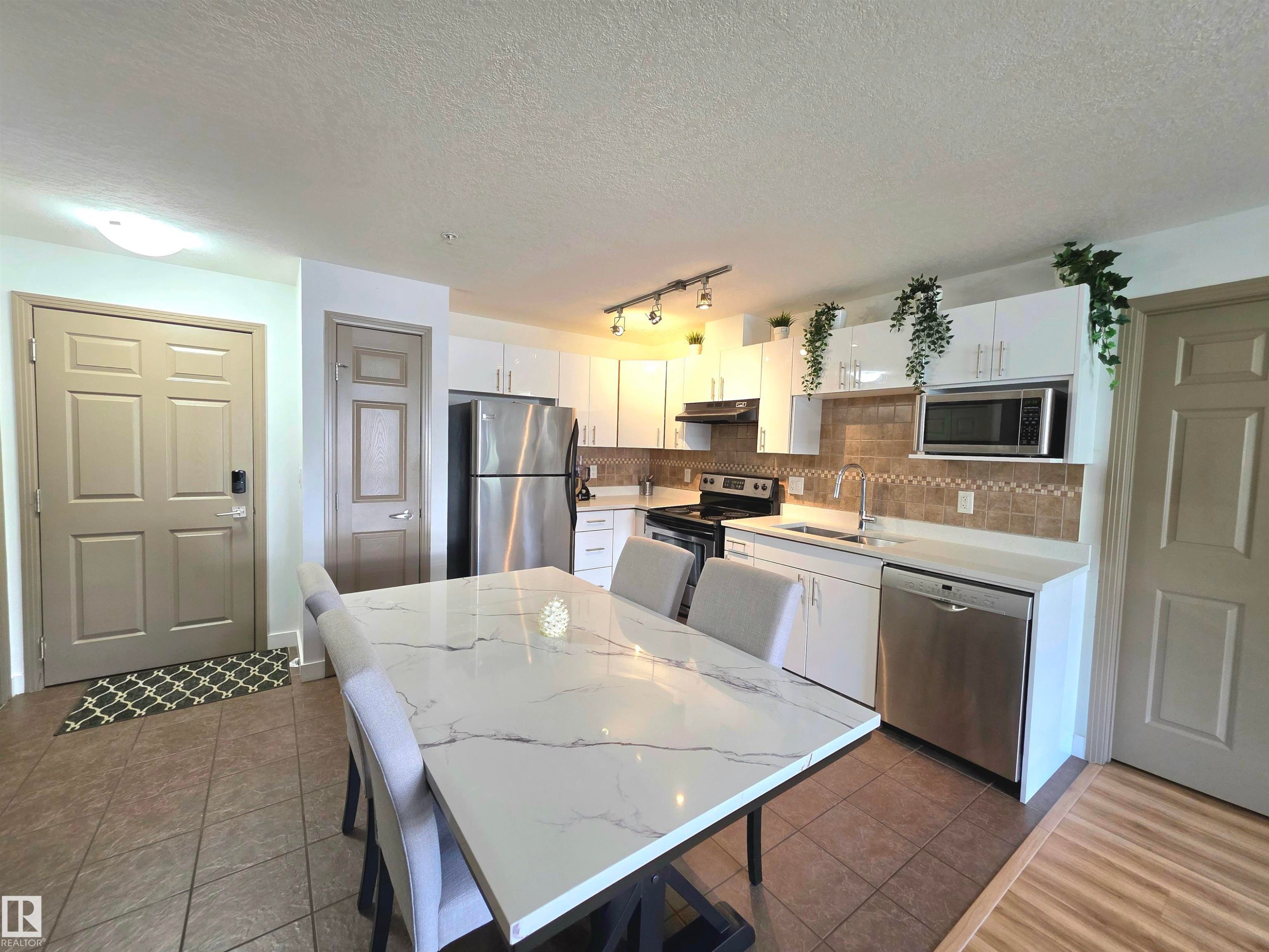 Open-concept kitchen and dining area featuring a spacious dining table with a marble-look top - 210 5005 165 Avenue, Edmonton, AB - Indoor Photo Showing Other Room