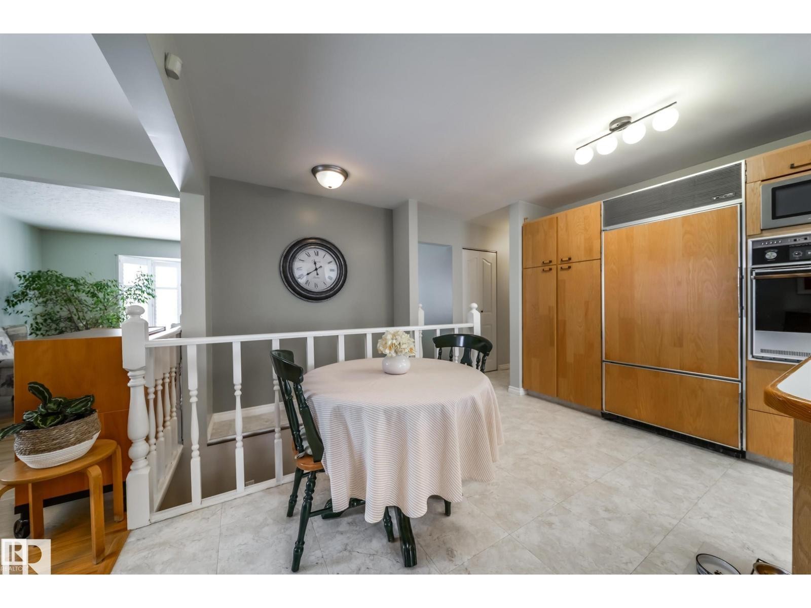 Kitchen featuring wood-finish cabinetry, integrated refrigerator, built-in oven, and a microwave - 10231 46 Street, Edmonton, AB