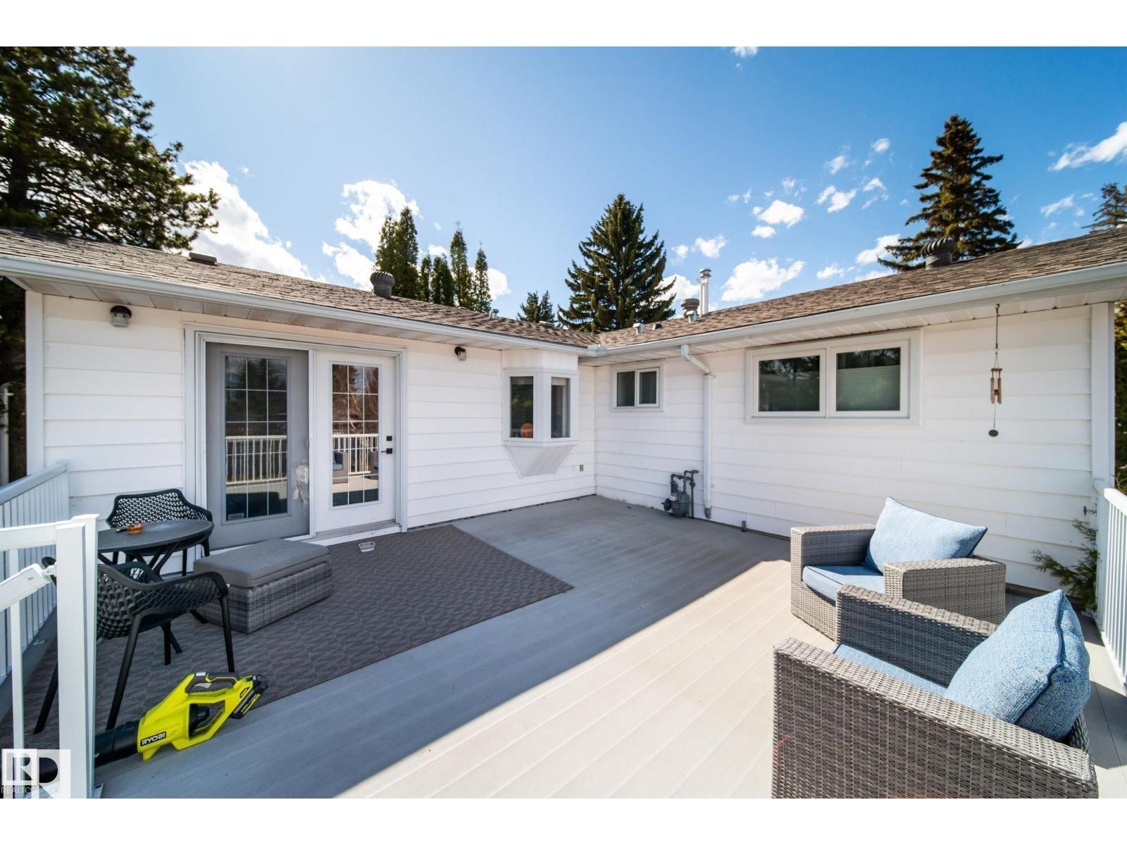 Spacious outdoor deck featuring light-toned composite decking, white railing, and a white siding exterior - 10231 46 Street, Edmonton, AB
