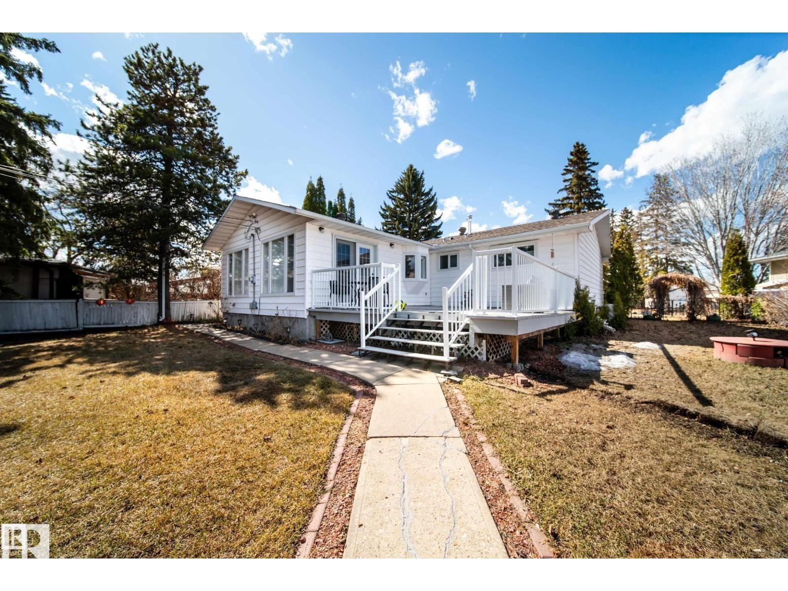 White-sided exterior featuring multiple windows and a sunroom extension - 10231 46 Street, Edmonton, AB