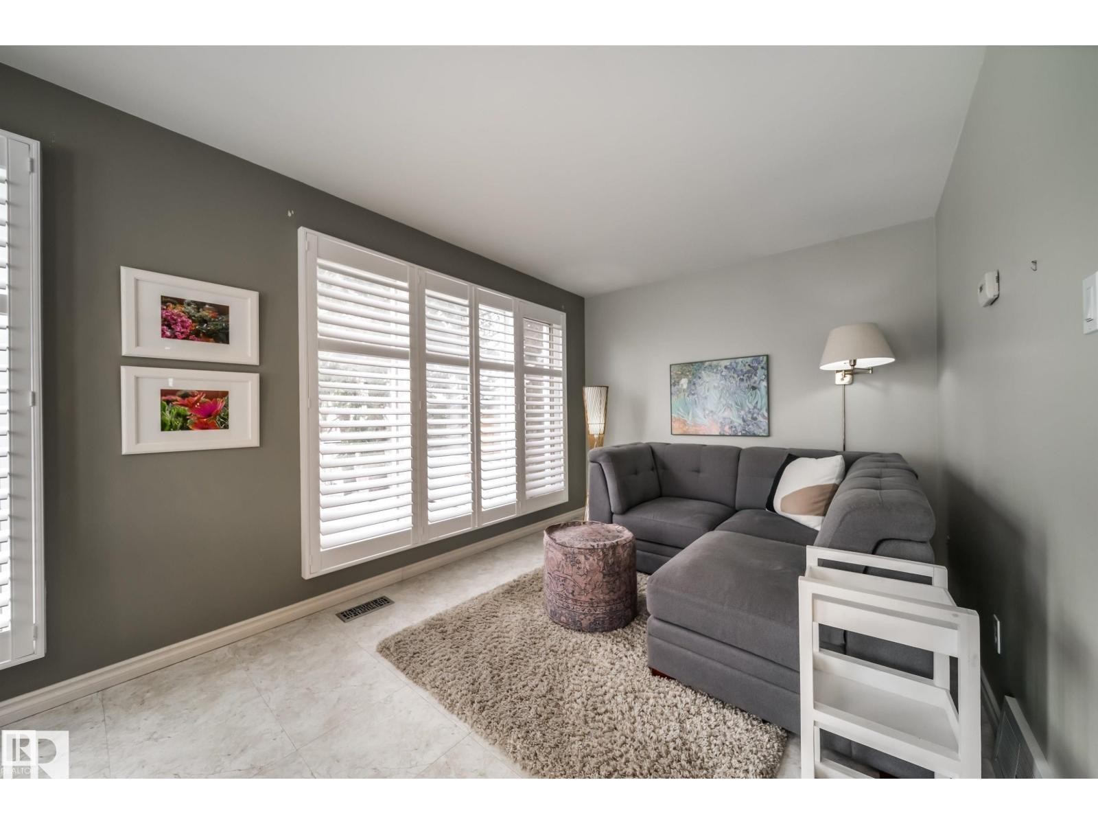 Living area featuring expansive windows with white plantation shutters, light-toned tile flooring, and neutral wall tones - 10231 46 Street, Edmonton, AB