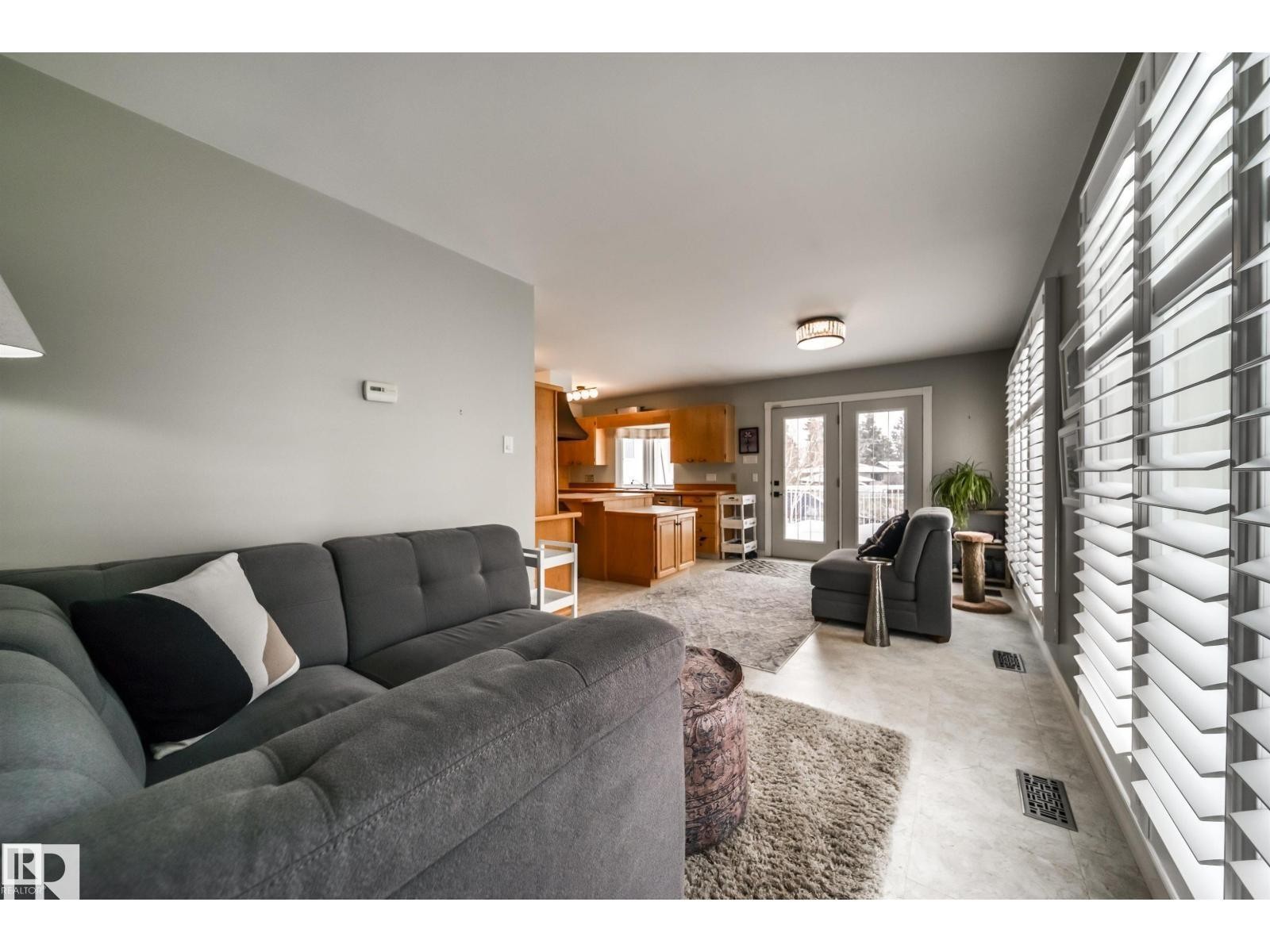 Living area featuring extensive window treatments, light-toned flooring, and a contemporary ceiling light fixture - 10231 46 Street, Edmonton, AB