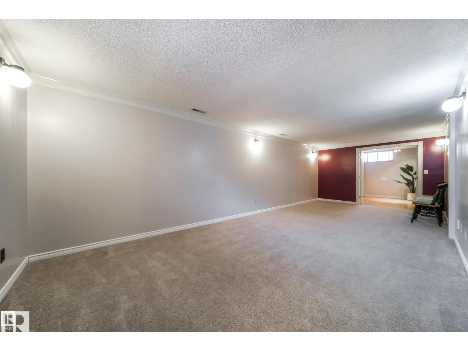 Spacious carpeted room featuring crown molding, neutral wall tones, and recessed lighting - 10231 46 Street, Edmonton, AB