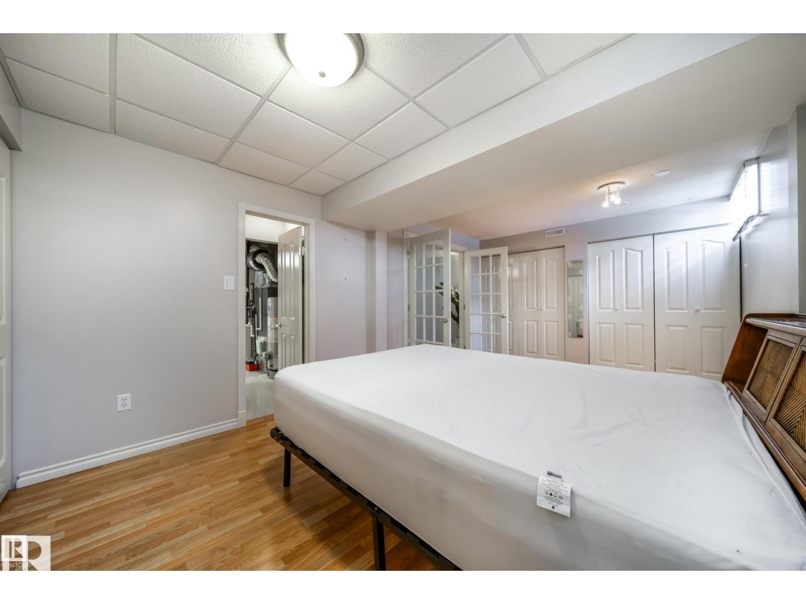 Bright interior with light wood-finish flooring, white walls, and a drop ceiling - 10231 46 Street, Edmonton, AB