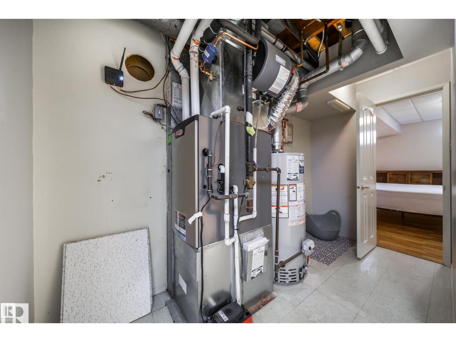 Utility area featuring a furnace, water heater, exposed ductwork, and tiled flooring - 10231 46 Street, Edmonton, AB