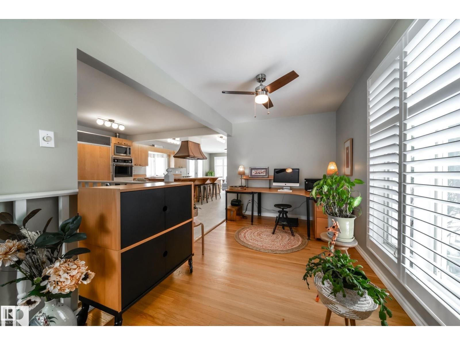 Bright interior space featuring wood-finish flooring and a ceiling fan - 10231 46 Street, Edmonton, AB