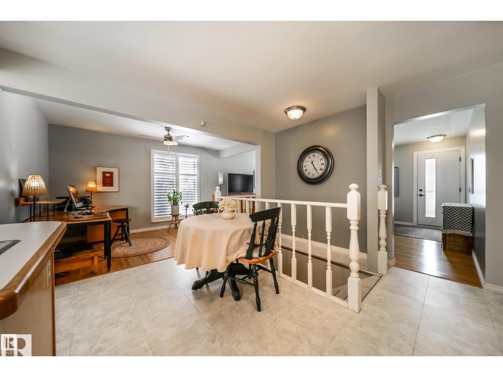 Open-concept living area with light-toned tile flooring, wood-finish flooring, and a white baluster railing - 10231 46 Street, Edmonton, AB