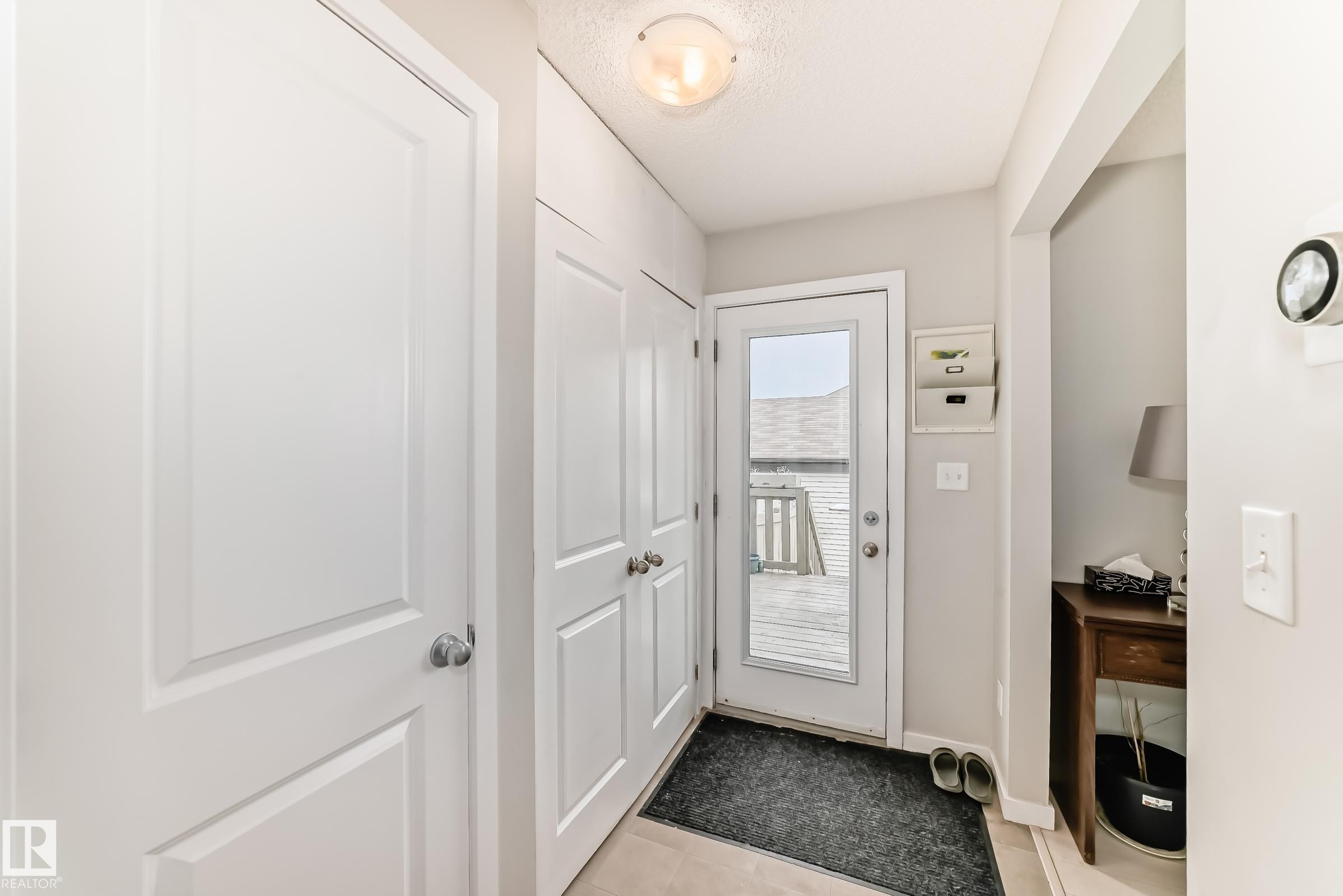 Entryway featuring a glass-paned exterior door, built-in storage cabinets, neutral wall paint, and light-toned flooring - 328 Watt Boulevard, Edmonton, AB - Indoor Photo Showing Other Room