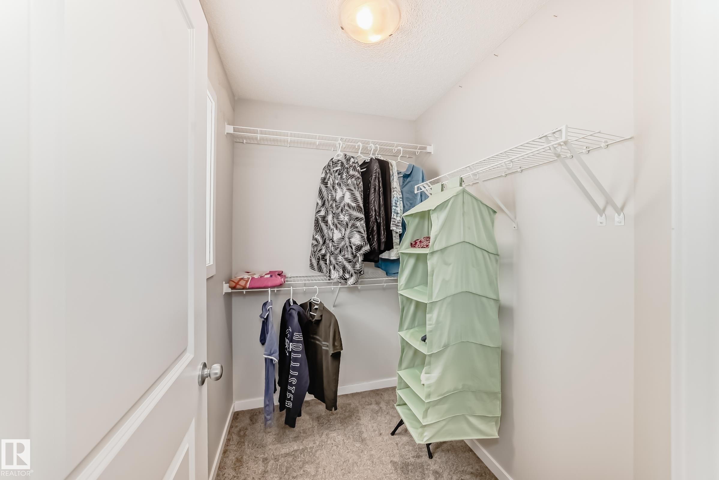 Walk-in closet featuring wire shelving, wire hanging rods, neutral wall paint, textured ceiling, and carpeting - 328 Watt Boulevard, Edmonton, AB - Indoor With Storage
