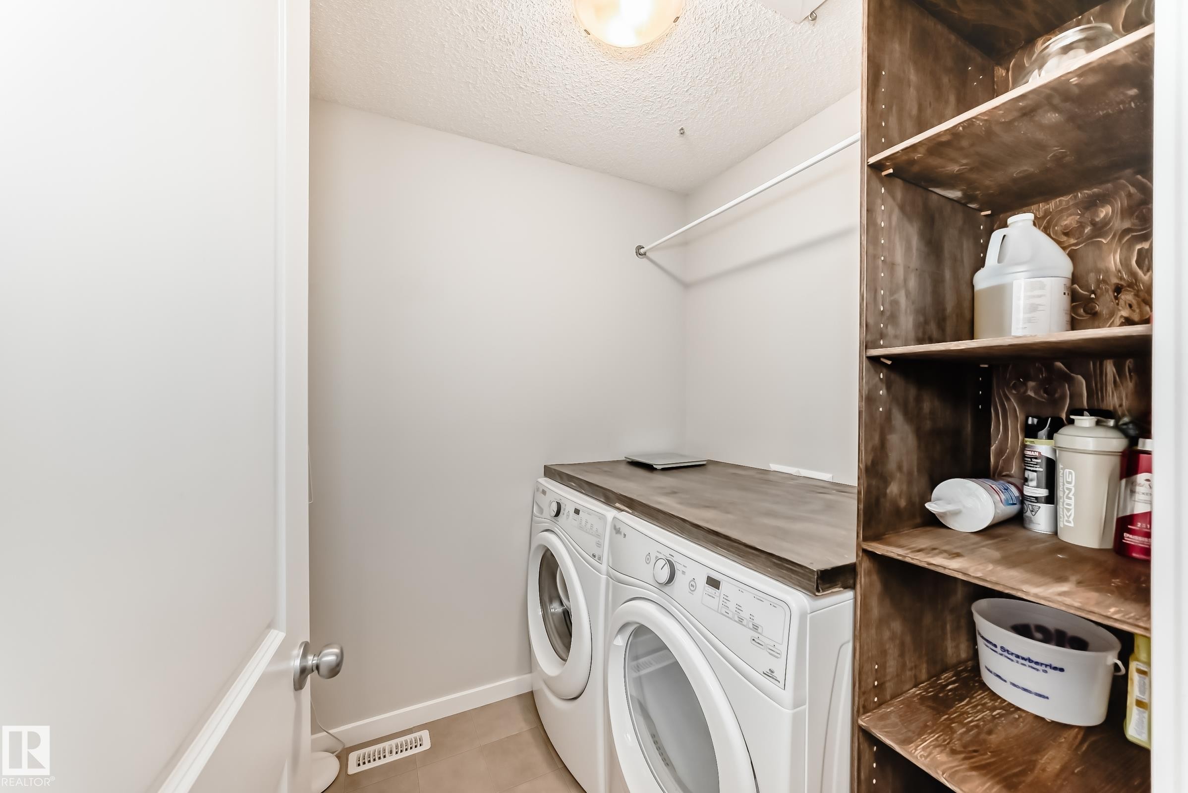 Dedicated laundry area featuring a countertop over front-load appliances, a clothes hanging rod, and integrated wood-finish shelving - 328 Watt Boulevard, Edmonton, AB - Indoor Photo Showing Laundry Room