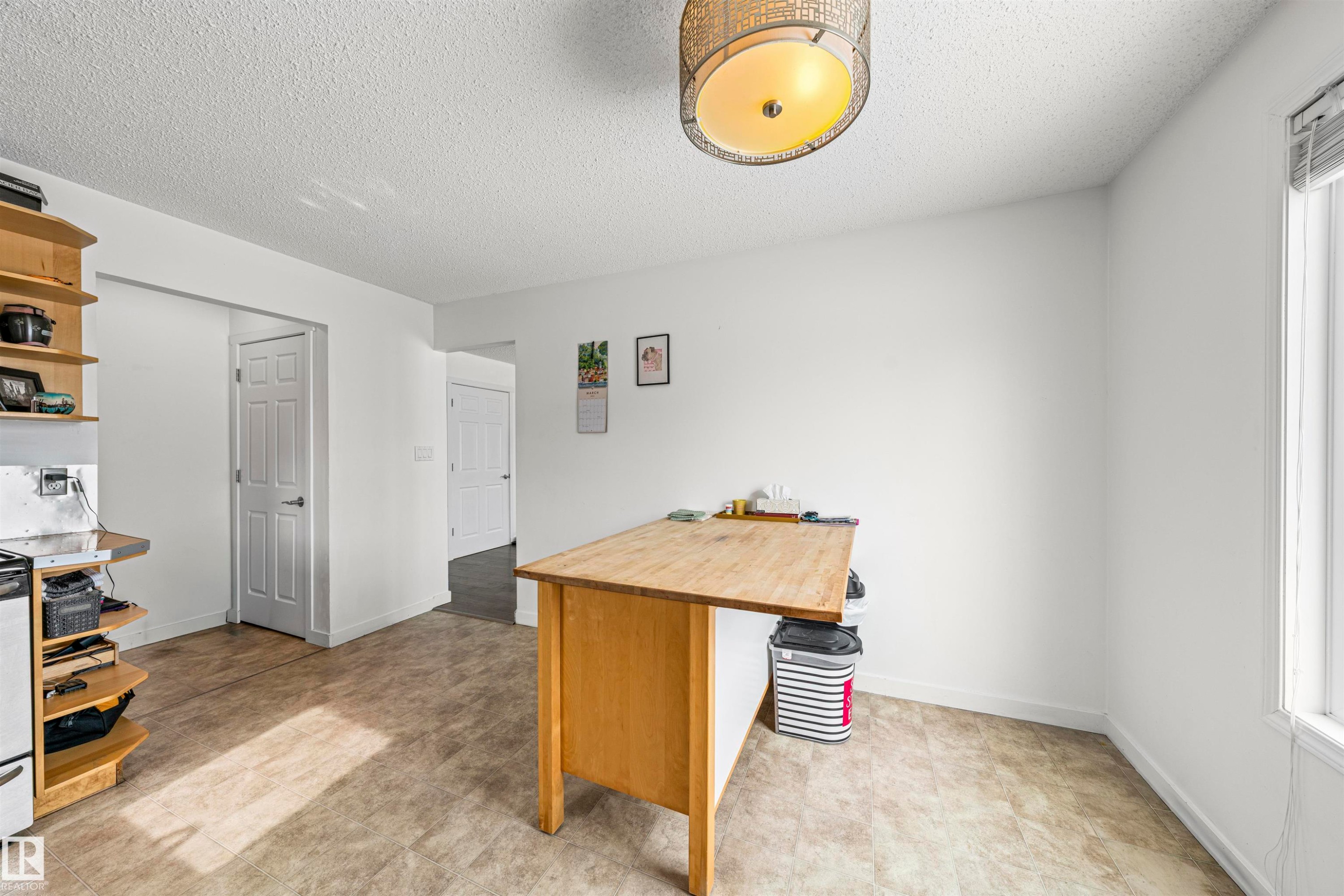 Spacious room with durable wood-finish flooring, bright white walls, and a recessed window with vertical blinds - 115 Warwick Road, Edmonton, AB - Indoor