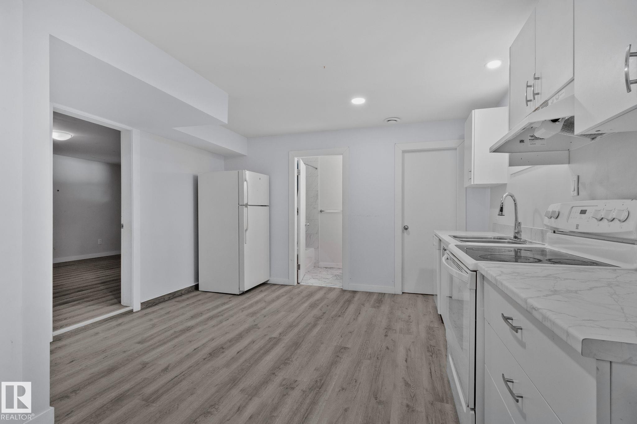 Kitchen featuring white cabinetry, wood-finish flooring, undermount double-basin sink, electric range, and refrigerator - 12002 37 Street, Edmonton, AB - Indoor Photo Showing Other Room