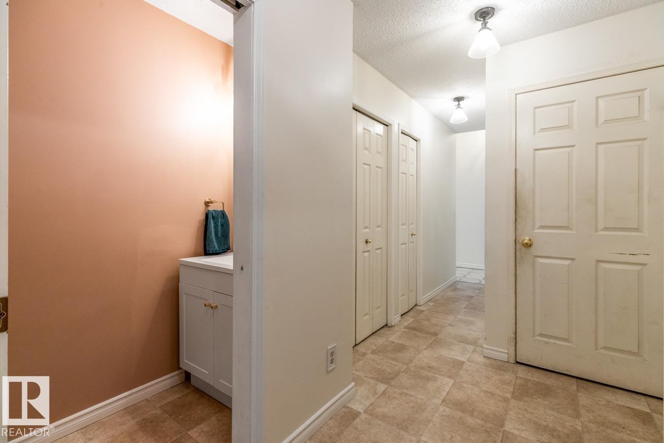 Hallway featuring neutral-toned floor tiling, two flush-mount ceiling light fixtures, and a white paneled door - 4340 33 Street, Edmonton, AB - Indoor Photo Showing Other Room