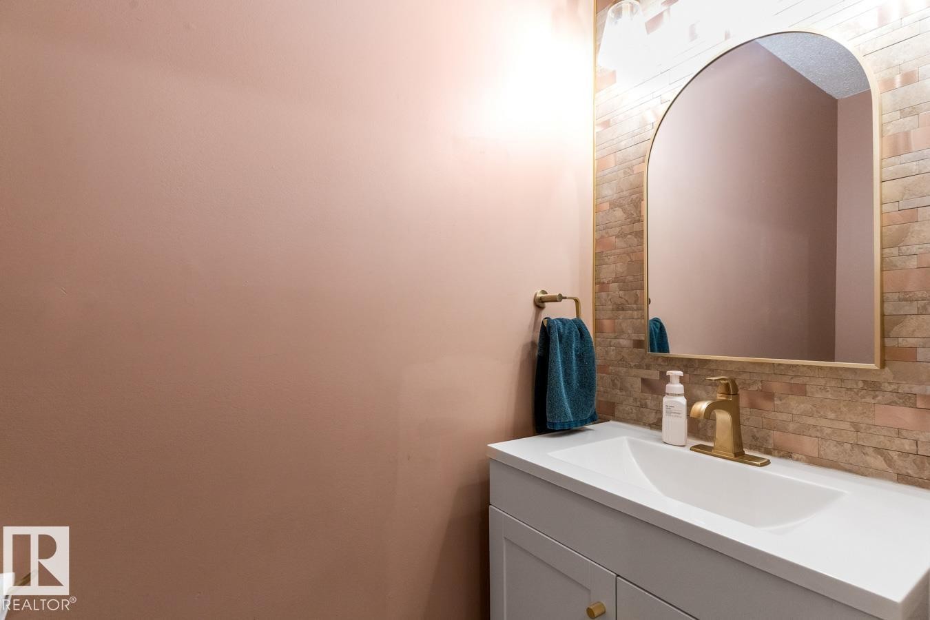 Vanity with an integrated white sink and a gold-finish faucet - 4340 33 Street, Edmonton, AB - Indoor Photo Showing Bathroom