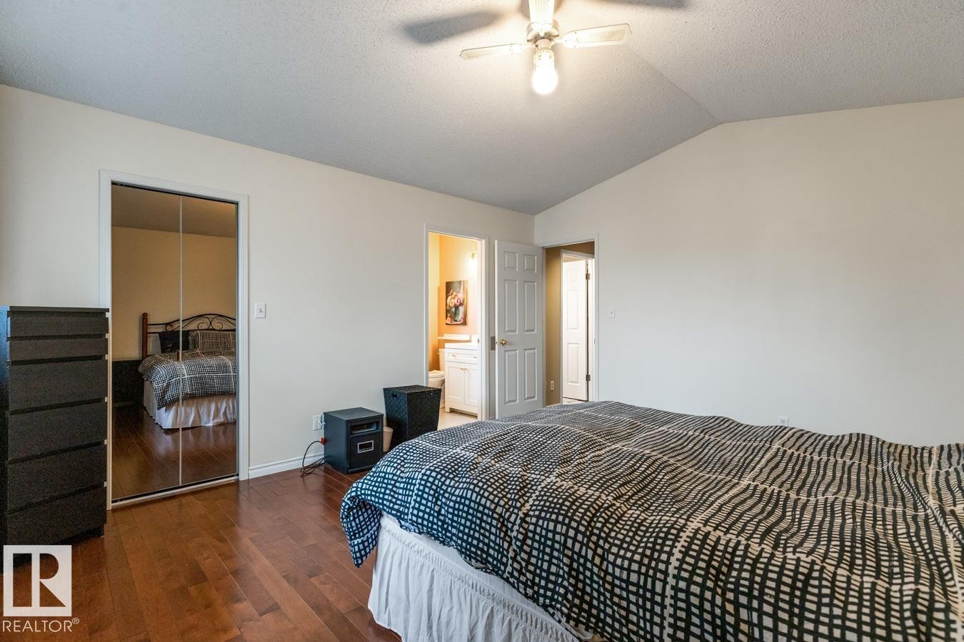 Bedroom with wood-finish flooring, mirrored closet doors, and an overhead ceiling fan light fixture - 4340 33 Street, Edmonton, AB - Indoor Photo Showing Bedroom