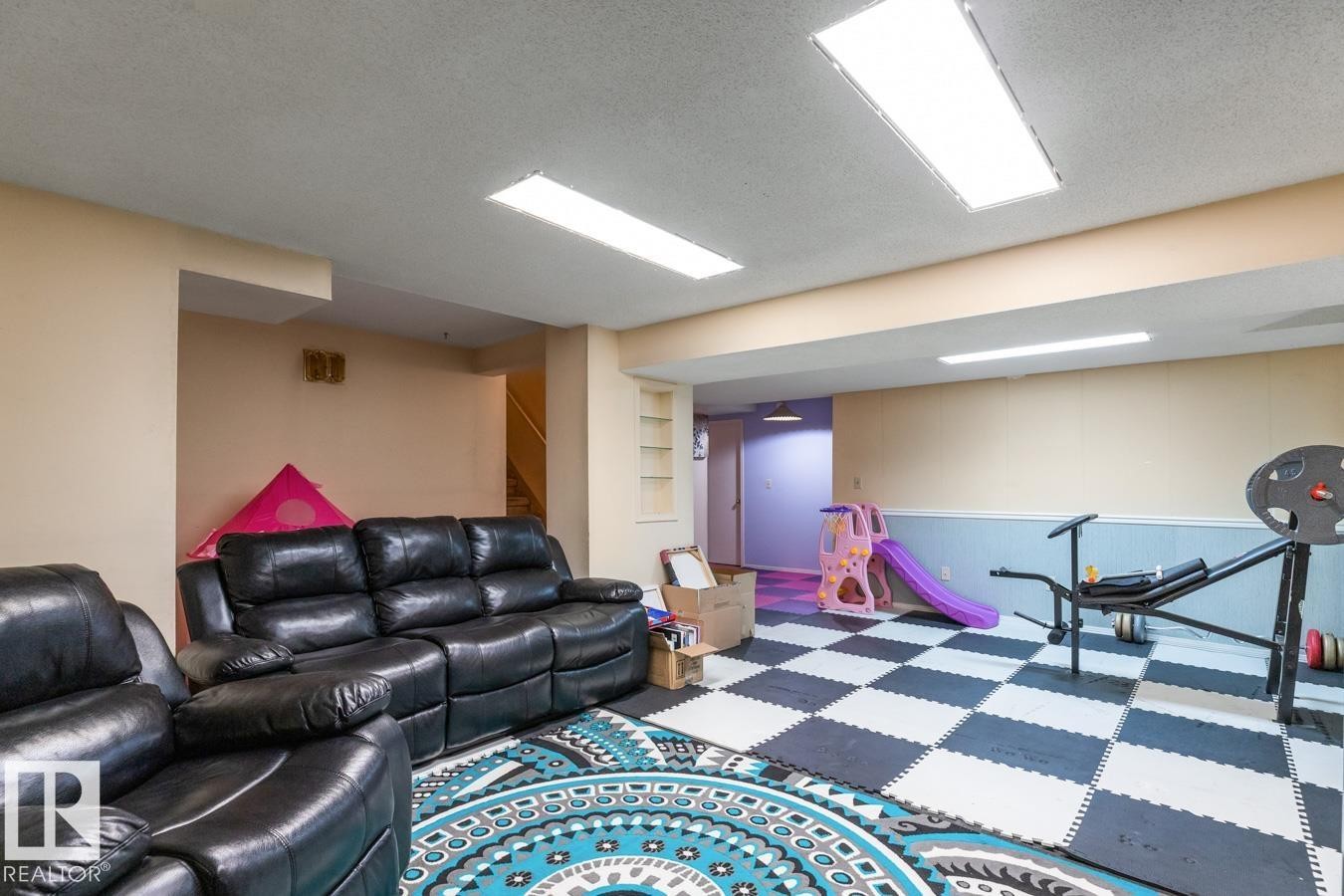Spacious lower level featuring recessed lighting, a neutral color palette, built-in shelving, and a combination of carpeted and checkerboard flooring - 4340 33 Street, Edmonton, AB - Indoor Photo Showing Basement