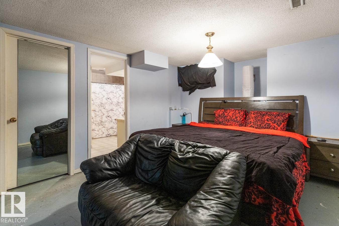 Interior room featuring a wood-finish headboard, light blue walls, a textured ceiling, a ceiling-mounted light fixture, and a mirrored closet door - 4340 33 Street, Edmonton, AB - Indoor Photo Showing Bedroom