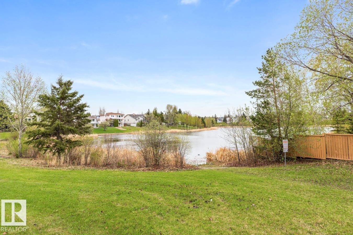 Expansive green lawn bordering a body of water with natural reeds - 4340 33 Street, Edmonton, AB - Outdoor With View