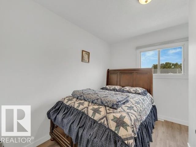 Bedroom featuring a window with natural light, wood-finish flooring, and crisp white walls - 3602 50Th Ave, Sylvan Lake, AB - Indoor Photo Showing Bedroom