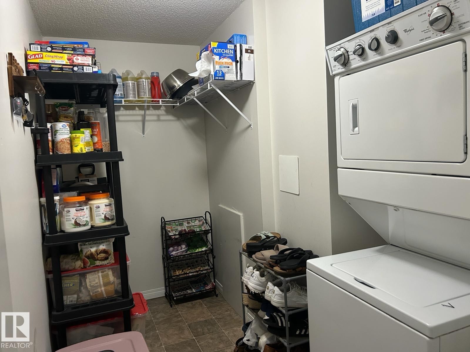 Dedicated laundry space featuring a white stacked washer and dryer unit - 1228 9363 Simpson Drive, Edmonton, AB - Indoor Photo Showing Laundry Room