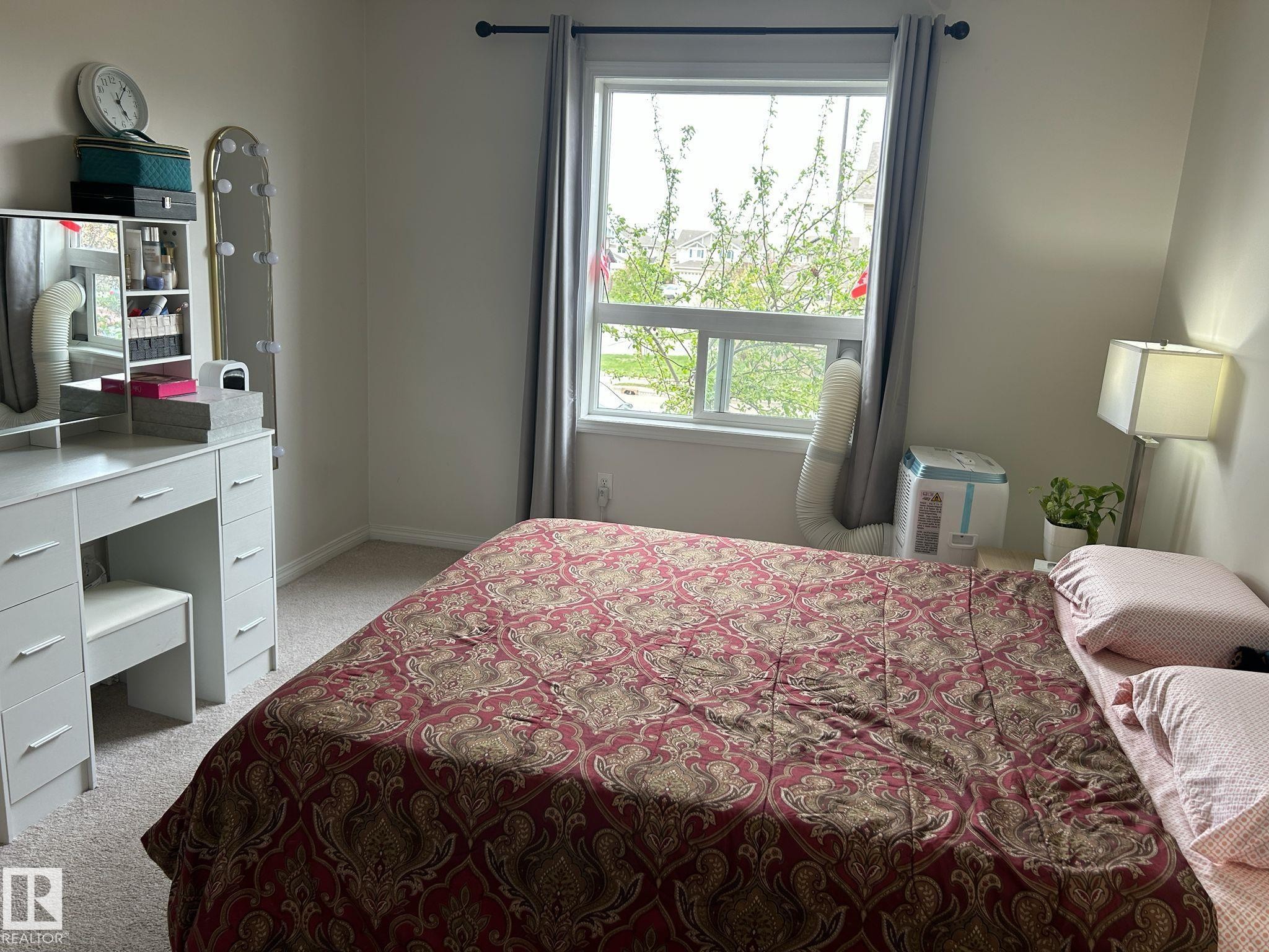 Carpeted room with a double-hung window featuring a dark rod and grey curtains - 1228 9363 Simpson Drive, Edmonton, AB - Indoor Photo Showing Bedroom