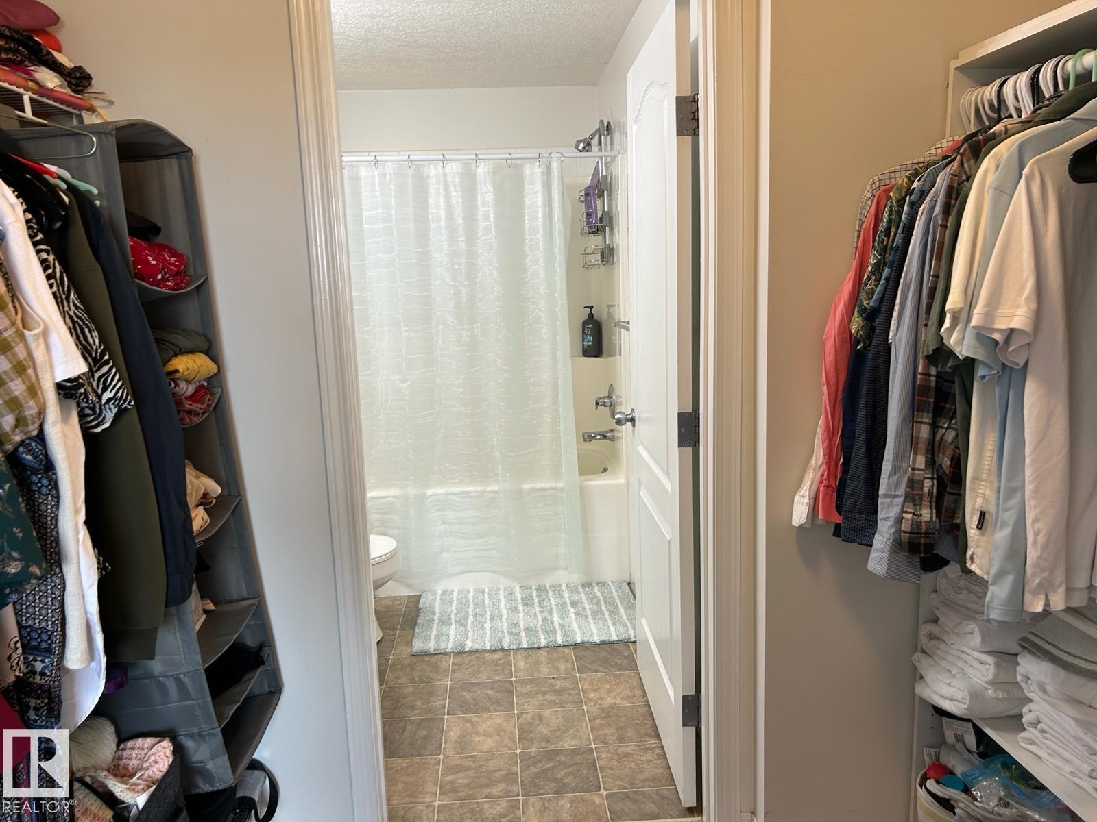 Bathroom featuring a white tub, shower with a clear curtain, and tile flooring - 1228 9363 Simpson Drive, Edmonton, AB - Indoor With Storage
