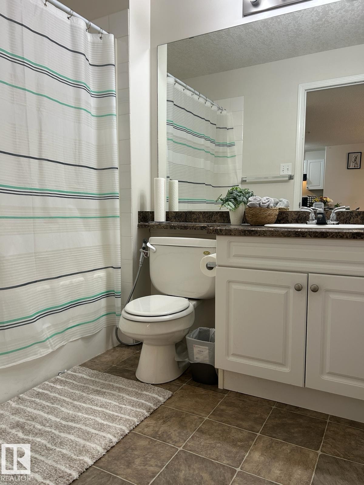 Bathroom featuring a white vanity with paneled doors, a dark stone-finish countertop, and a large wall-mounted mirror - 1228 9363 Simpson Drive, Edmonton, AB - Indoor Photo Showing Bathroom