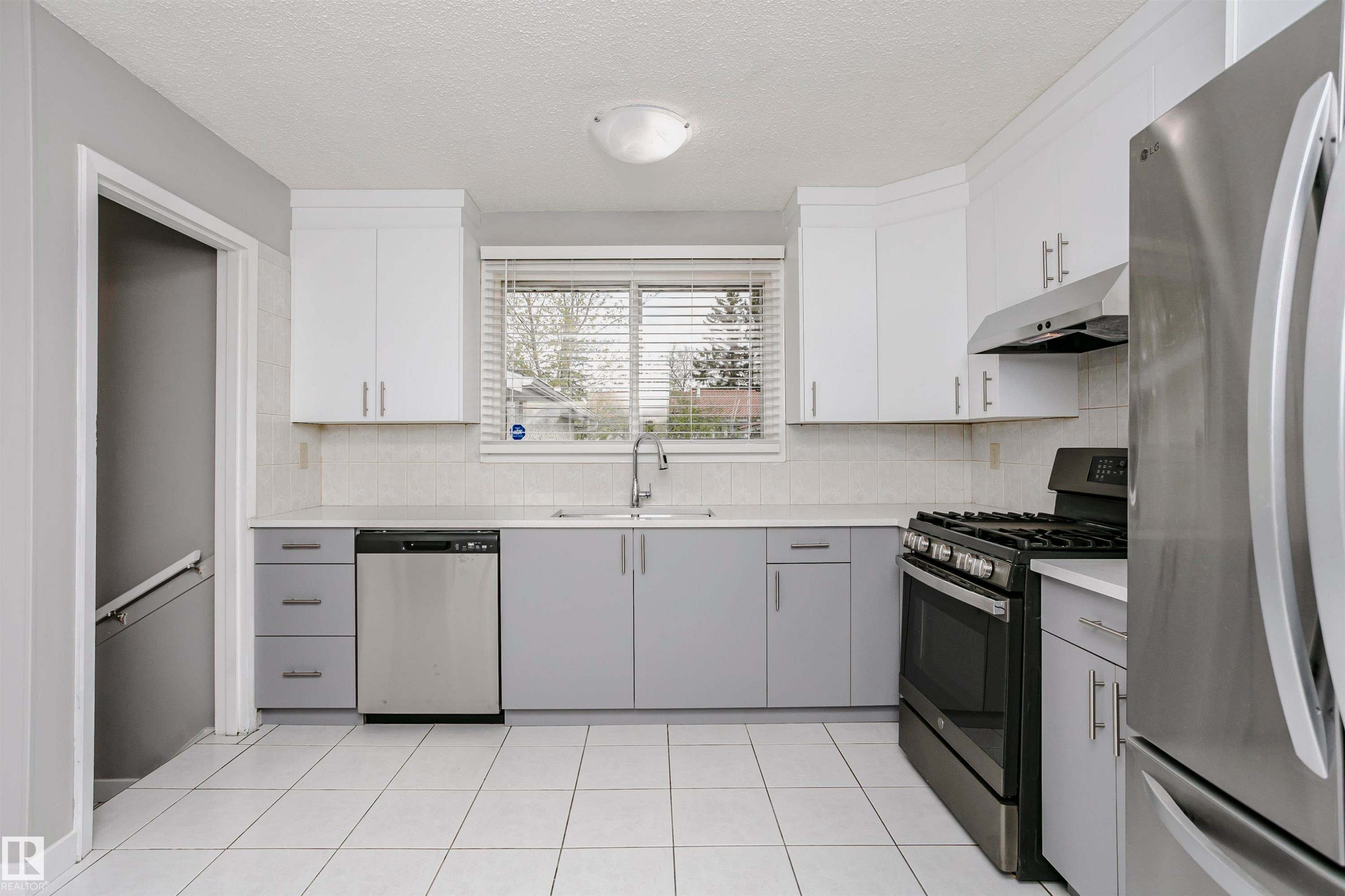 Spacious country kitchen with large dinette area & st/steel appliances. Beautiful new custom cabinetry and quartz countertops. Undermount st/st farmhouse sink & new faucet. Tile backsplash. New st/st fridge and dishwasher. Gas stove and hood fan. - 11436 161 Avenue, Edmonton, AB - Indoor Photo Showing Kitchen