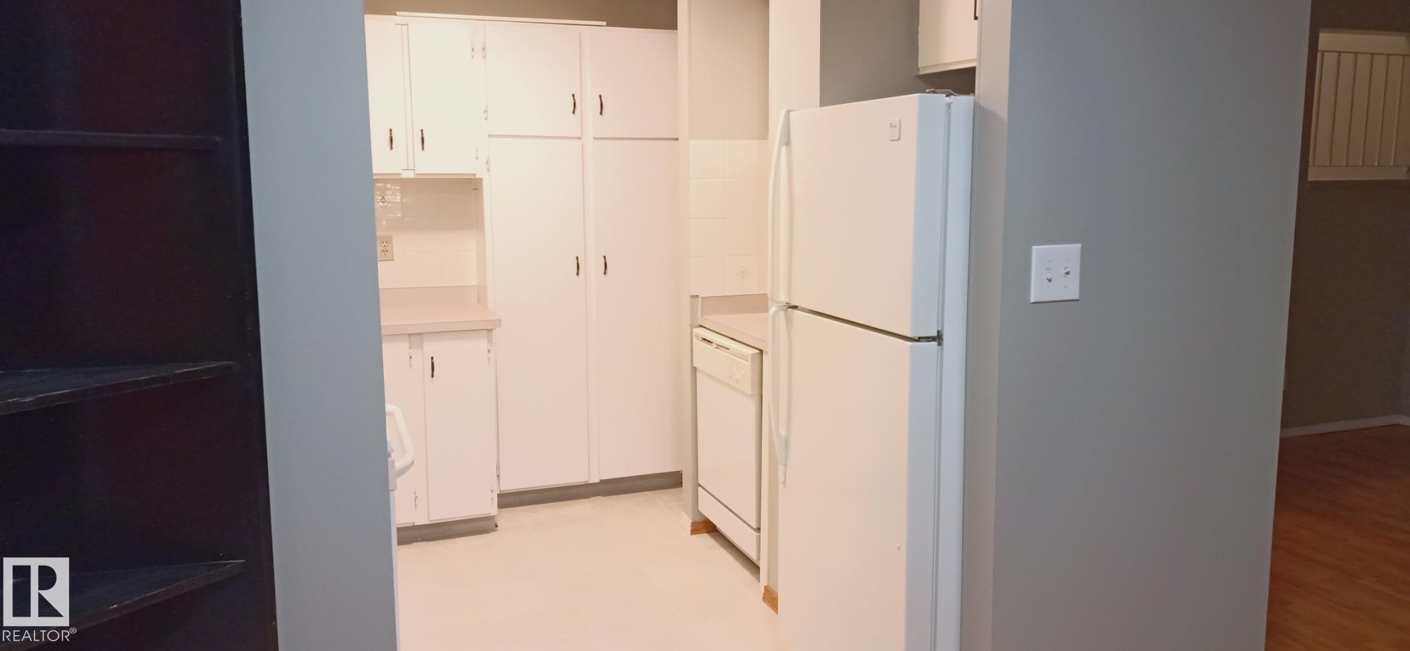 Kitchen featuring white cabinetry, light-toned countertops, tile flooring, and white appliances including a refrigerator and dishwasher - 2554 79 Street, Edmonton, AB - Indoor