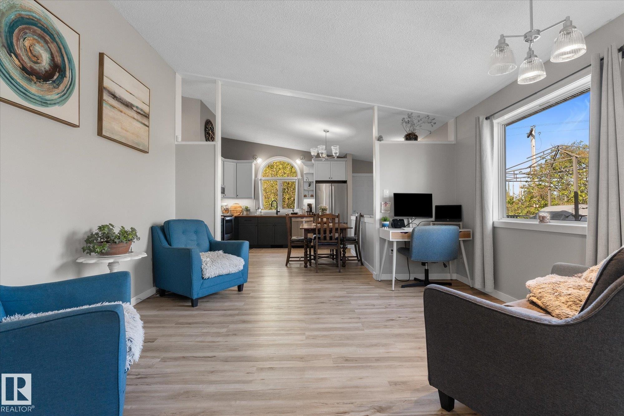 Open concept living area featuring wood-finish flooring, light gray wall paint, and a large window - 4759 48 Street, Onoway, AB - Indoor Photo Showing Other Room