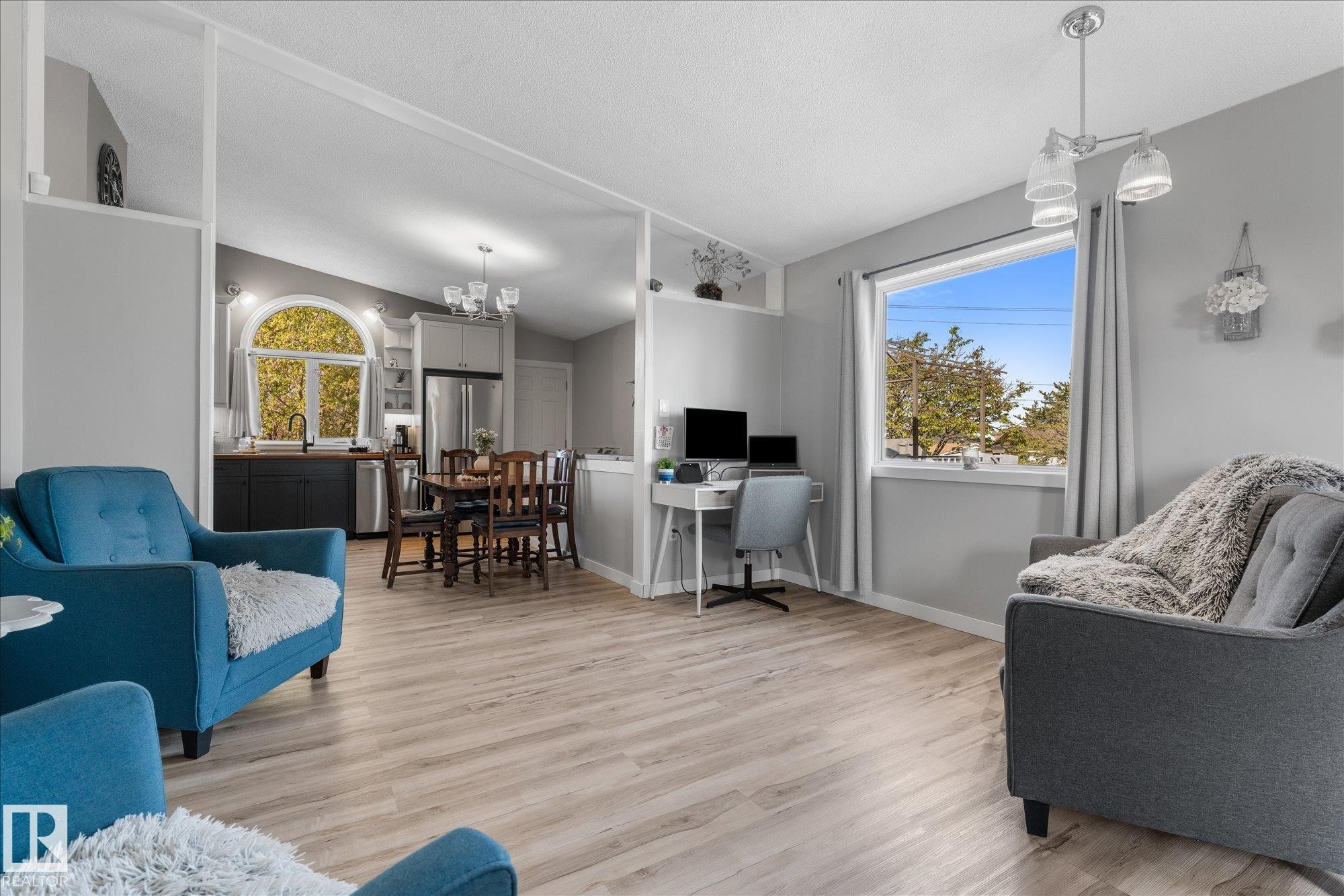 Open-concept living space featuring light wood-finish flooring, a contemporary ceiling light fixture, and a large window - 4759 48 Street, Onoway, AB - Indoor Photo Showing Living Room