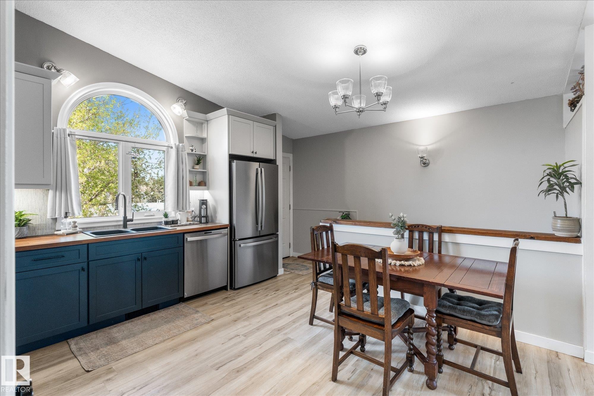Modern kitchen featuring an arched window, two-tone cabinetry, stainless steel appliances, and wood-finish countertops - 4759 48 Street, Onoway, AB - Indoor