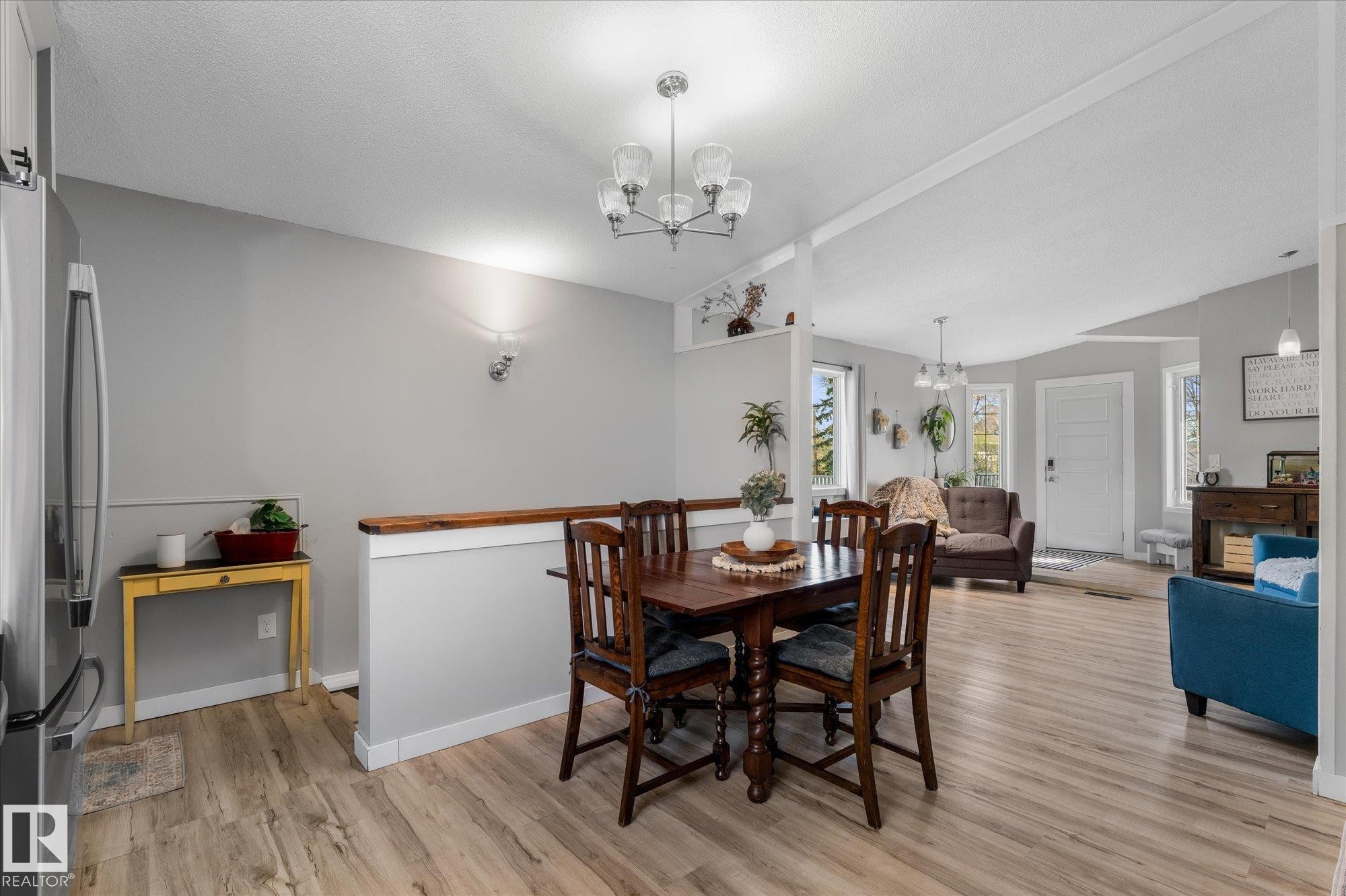 Dining area featuring a contemporary chandelier and wood-finish flooring - 4759 48 Street, Onoway, AB - Indoor Photo Showing Dining Room