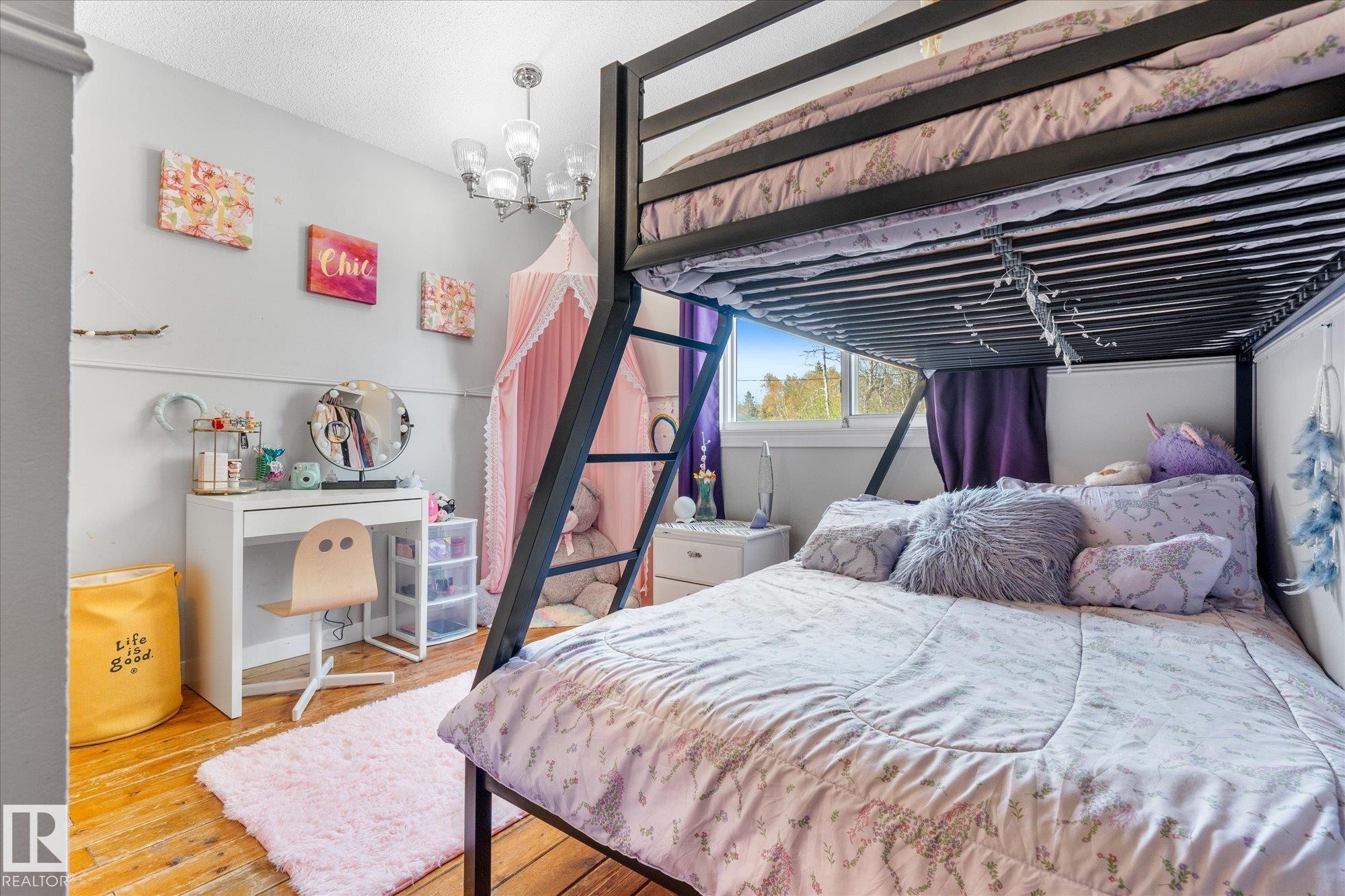 Room featuring a bunk bed frame, wood-finish flooring, a contemporary ceiling light fixture, a window with natural light, and a white vanity desk - 4759 48 Street, Onoway, AB - Indoor Photo Showing Bedroom