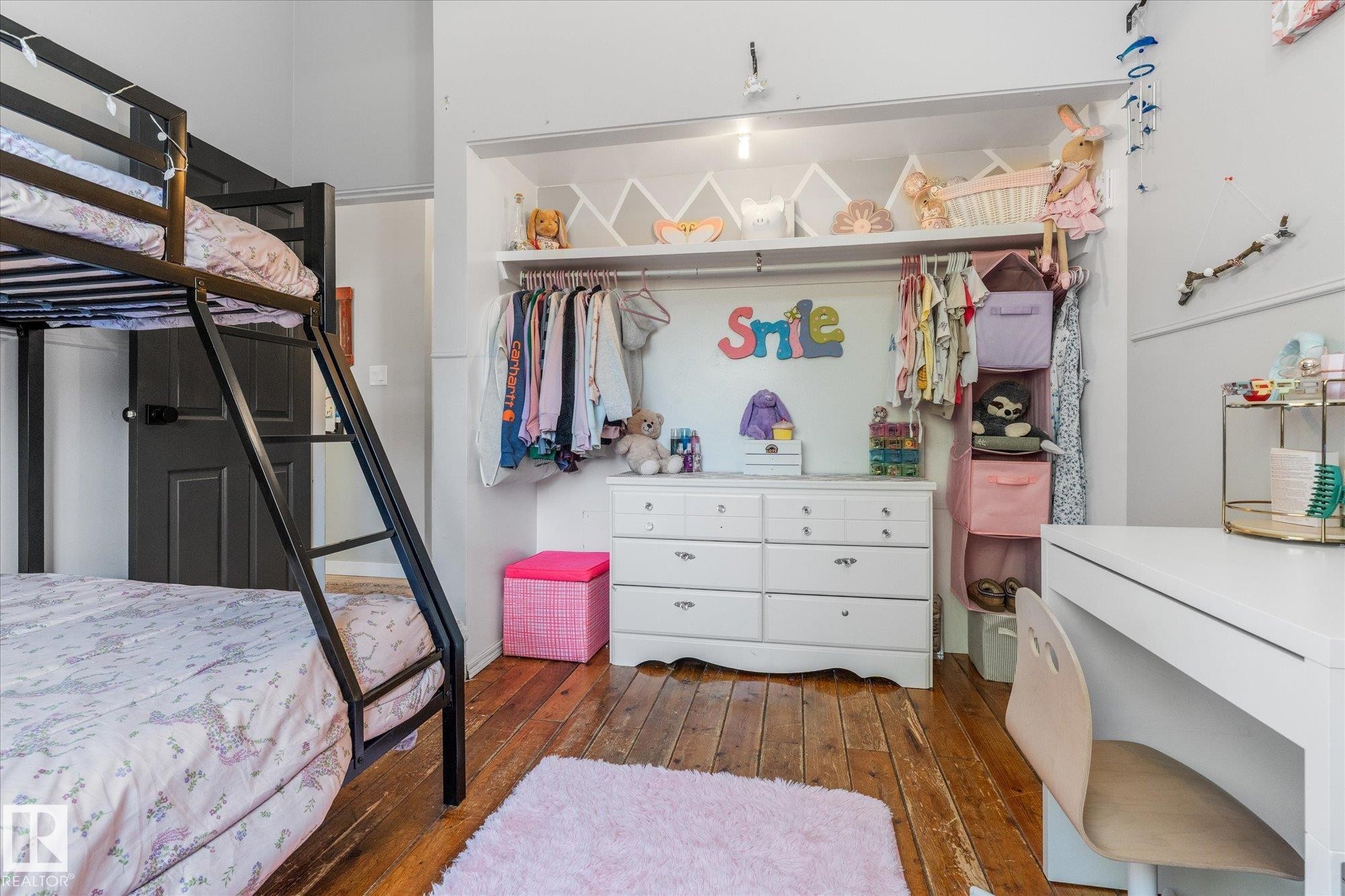 Hardwood flooring provides a durable surface throughout this room, complemented by a built-in closet system with shelving and hanging rods - 4759 48 Street, Onoway, AB - Indoor Photo Showing Bedroom