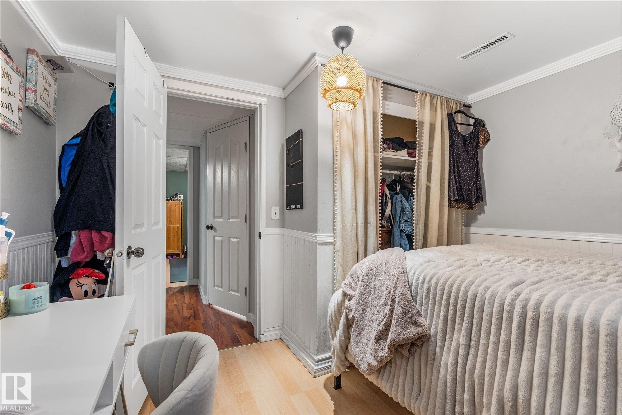 Light-toned wood-finish flooring with white wainscoting and crown molding - 4759 48 Street, Onoway, AB - Indoor