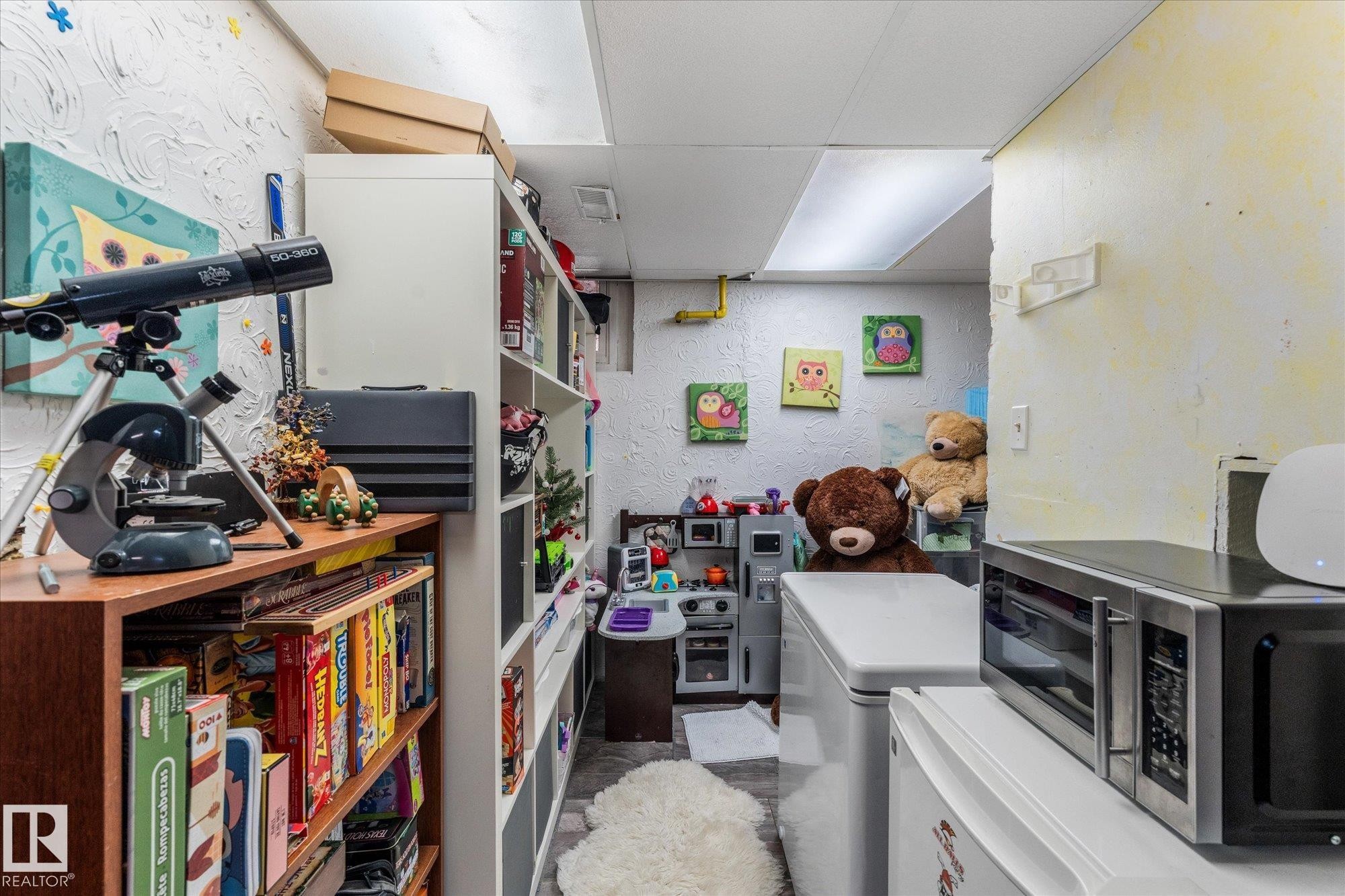 Compact utility space featuring built-in shelving, textured wall finishes, and overhead fluorescent lighting - 4759 48 Street, Onoway, AB - Indoor Photo Showing Other Room