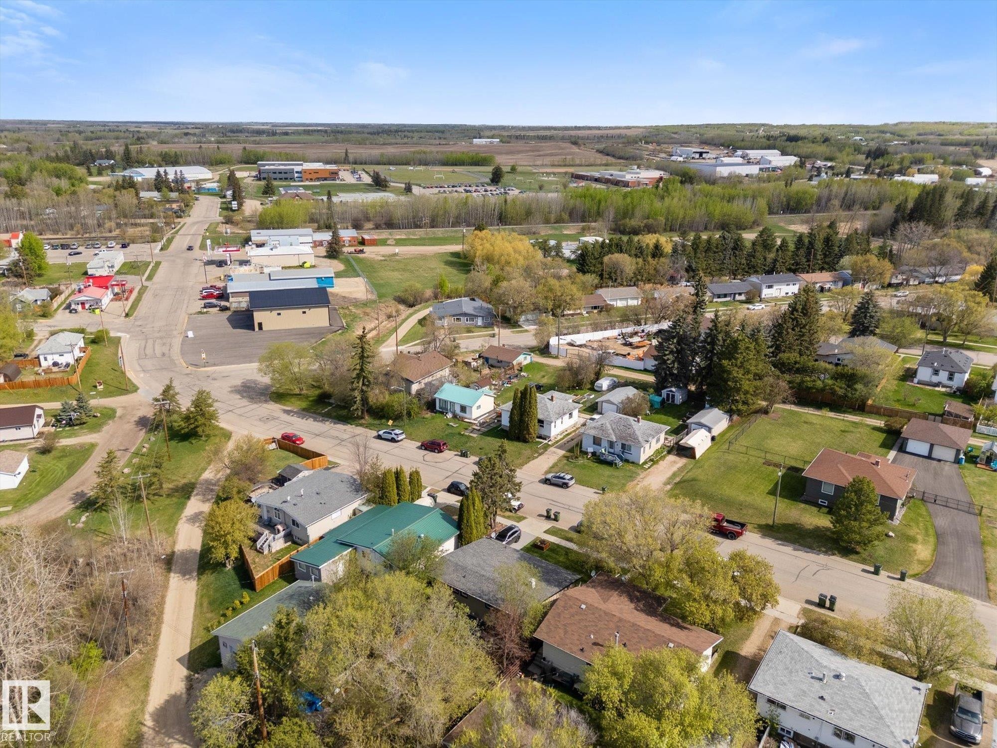 Aerial perspective showcasing a community with varied residential properties, surrounding green spaces, and a paved road network - 4759 48 Street, Onoway, AB - Outdoor With View