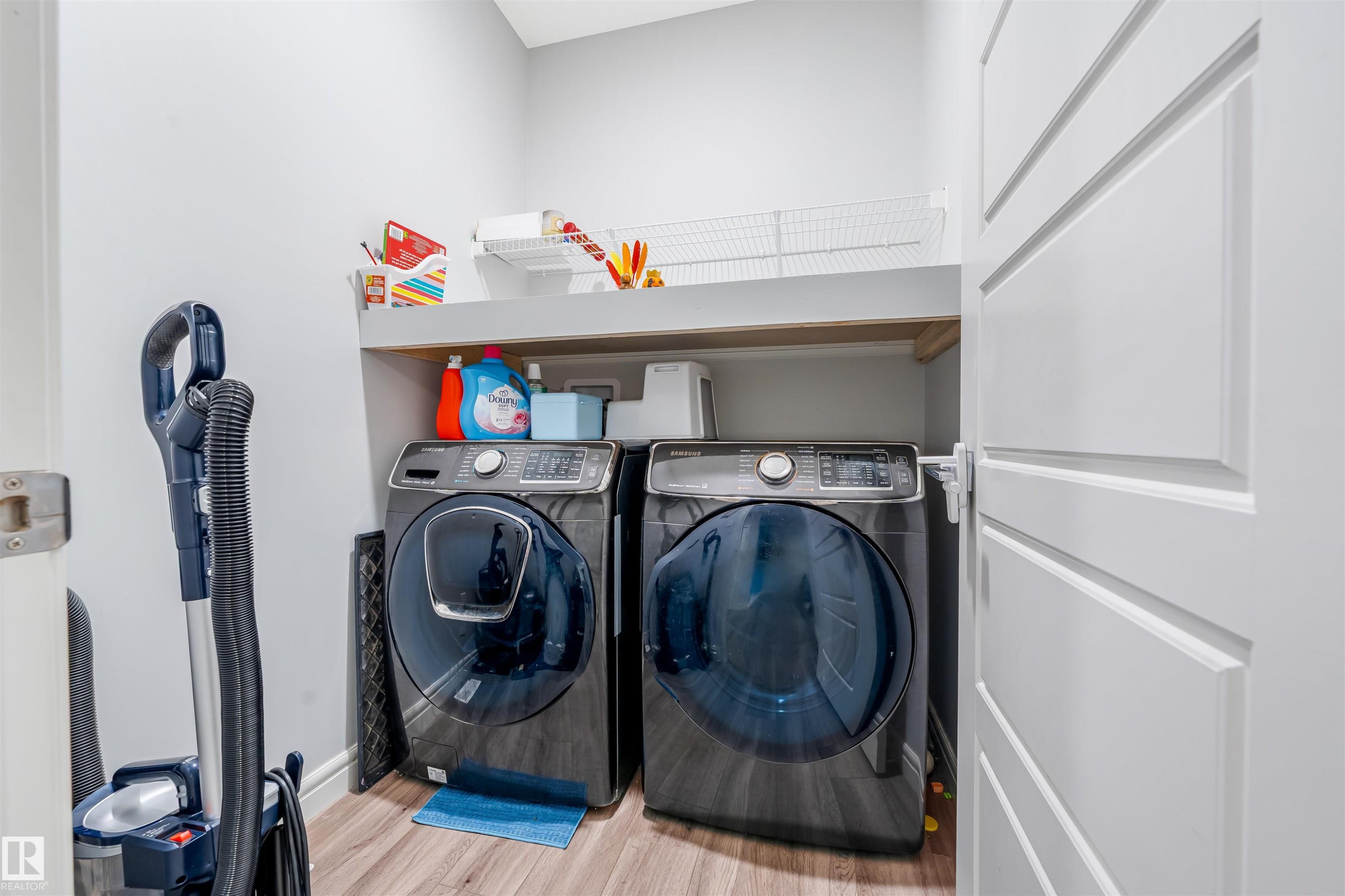 Dedicated laundry area featuring wood-finish flooring, white walls, and a built-in shelving unit for storage - 1024 Daniels Loop, Edmonton, AB - Indoor Photo Showing Laundry Room
