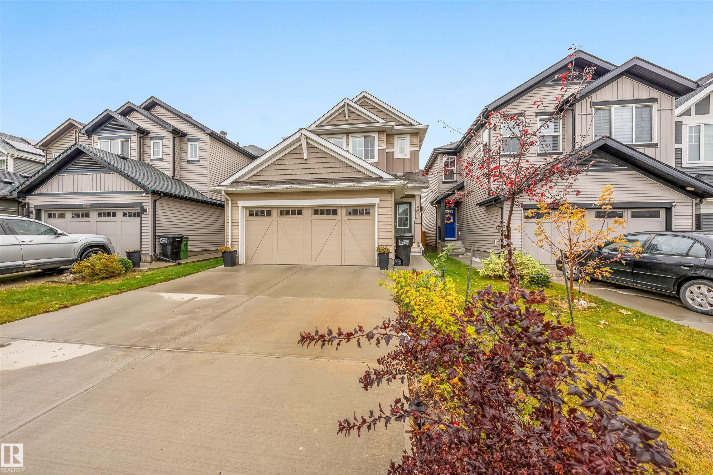 Two-story residence featuring a two-car garage with carriage-style doors, a concrete driveway, and neutral-toned siding - 1024 Daniels Loop, Edmonton, AB - Outdoor With Facade