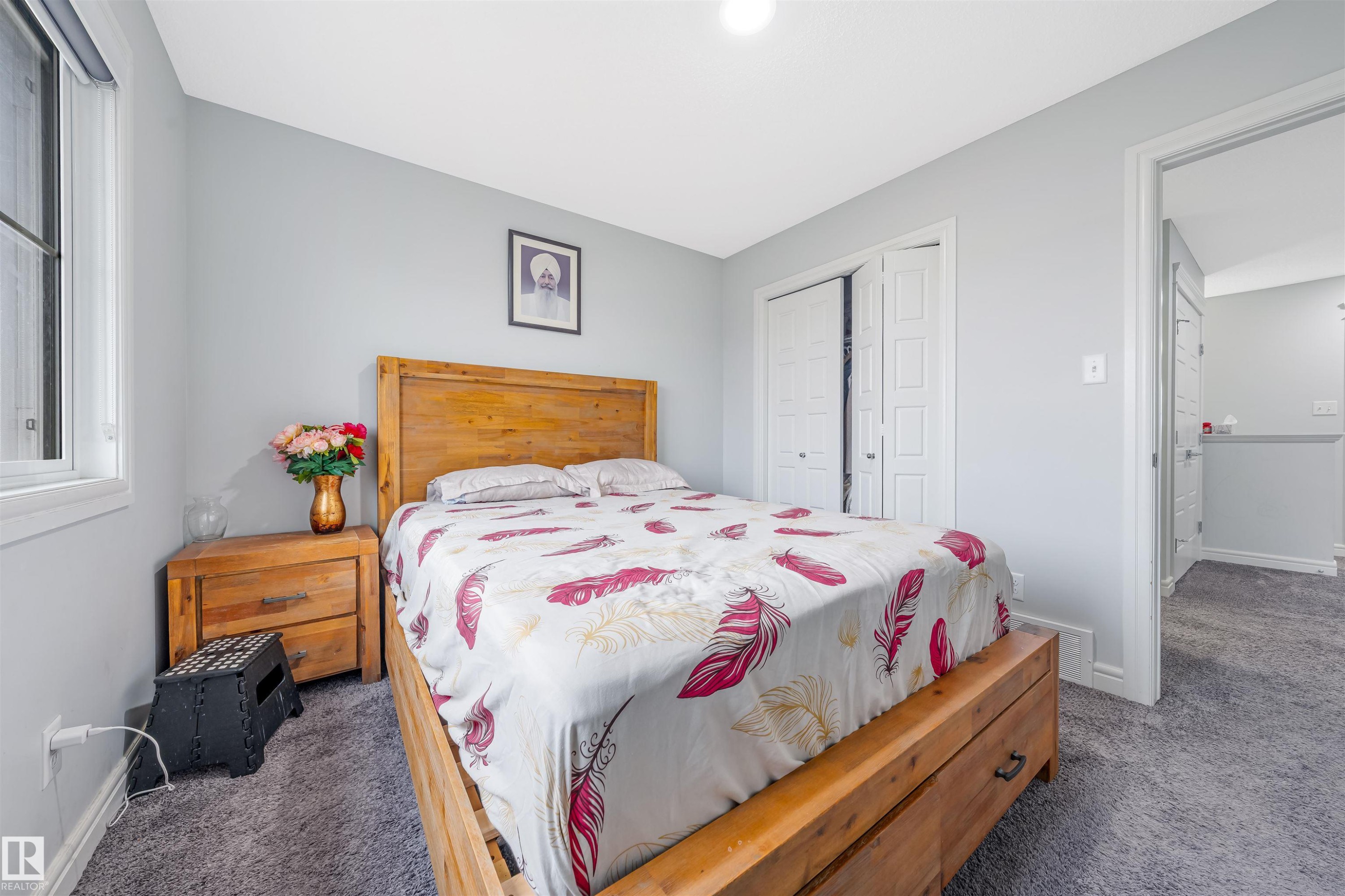 Carpeted room featuring light gray walls, a window with white trim, and white bi-fold closet doors - 1024 Daniels Loop, Edmonton, AB - Indoor Photo Showing Bedroom
