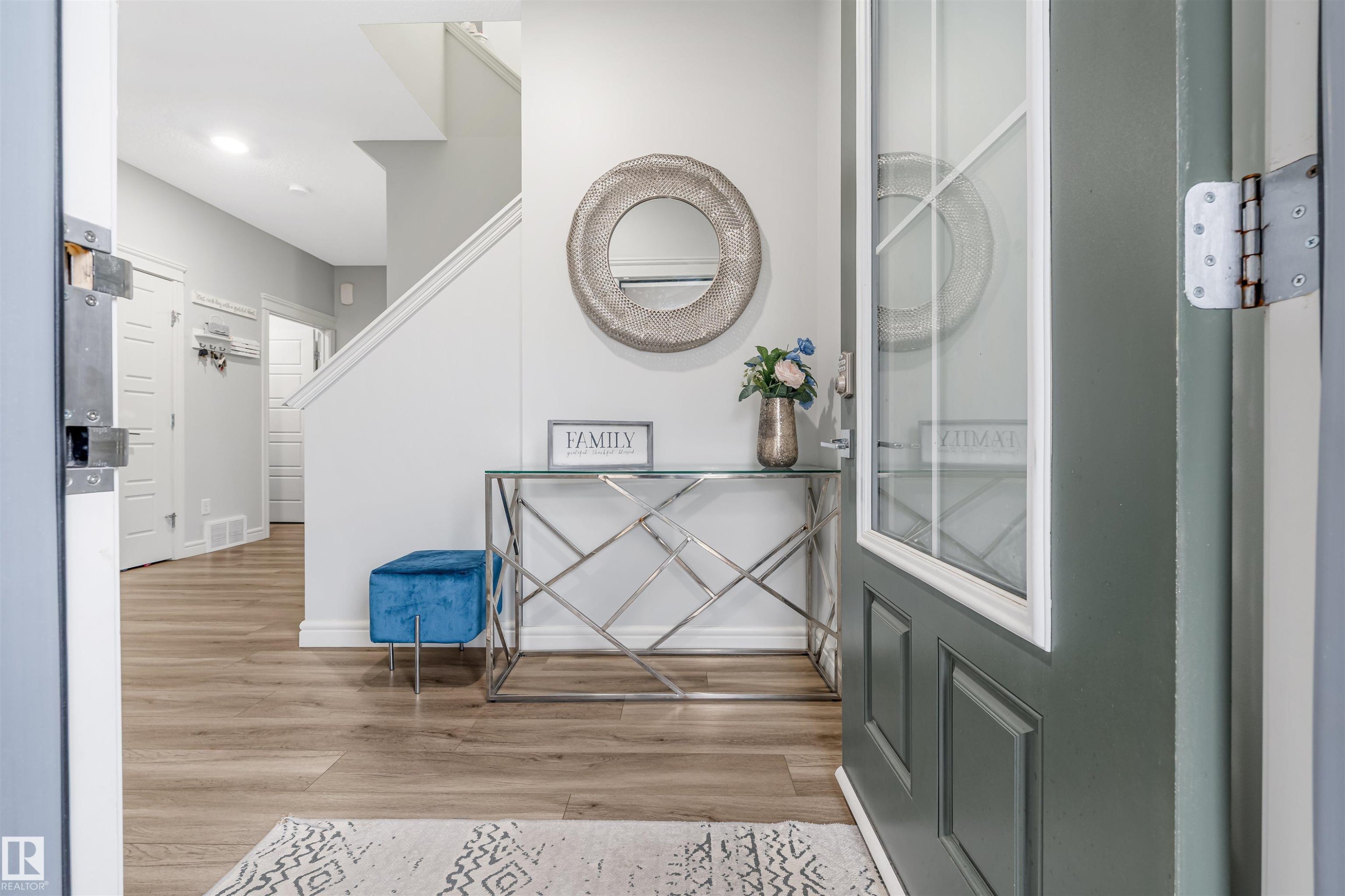 Entryway featuring a paneled door with glass insert, wood-finish flooring, and a staircase with white risers and handrails - 1024 Daniels Loop, Edmonton, AB - Indoor Photo Showing Other Room