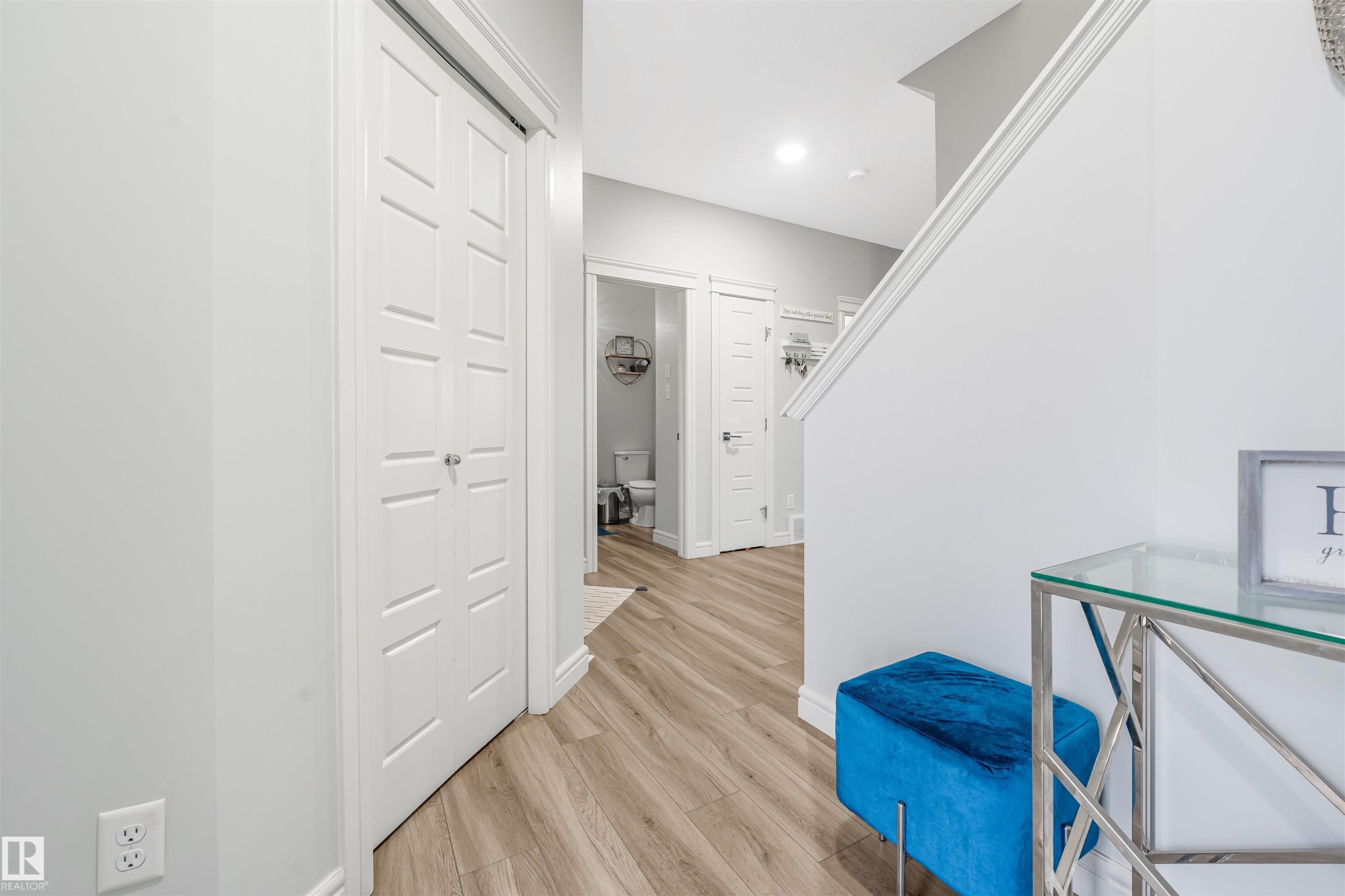 Open interior hallway featuring wood-finish flooring, white trim, and a white paneled bi-fold door - 1024 Daniels Loop, Edmonton, AB - Indoor Photo Showing Other Room